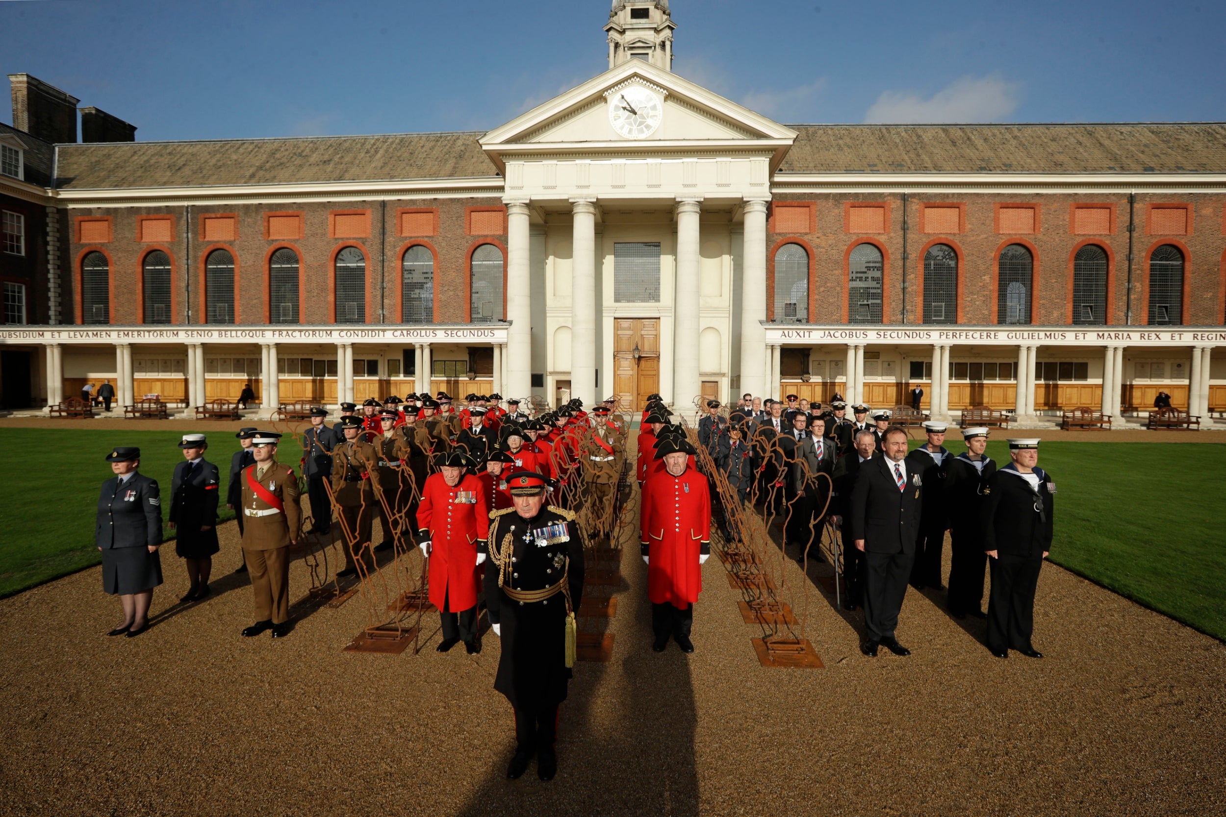 British General Lord Richard Dannatt, front centre, poses for a group photograph with Chelsea Pensioners, serving soldiers, serving airmen and women, Royal Navy reservists, military veterans and 6 foot ‘Tommy’ figures at the Royal Hospital Chelsea in London