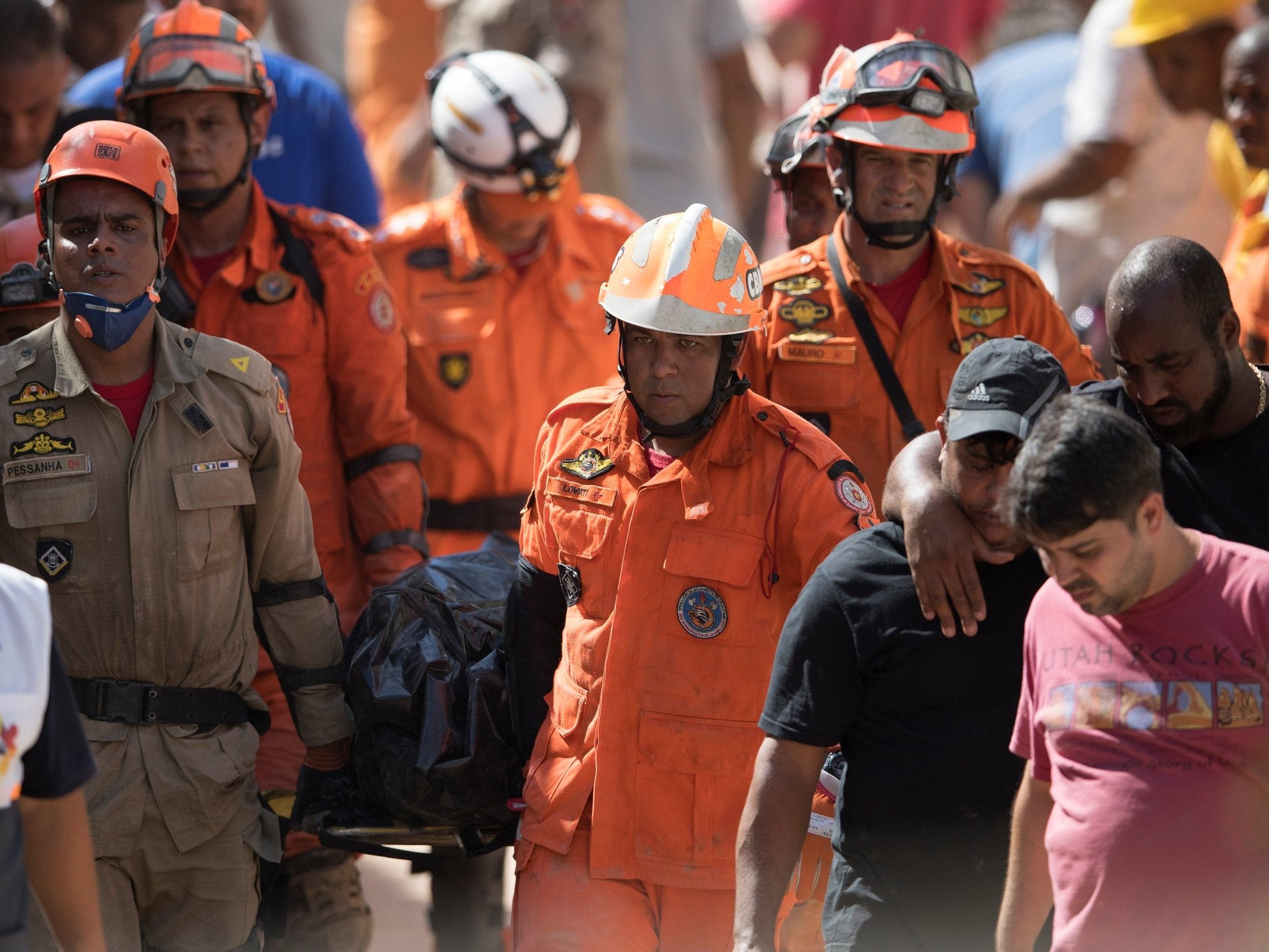 Firefighters carry a body found under the debris