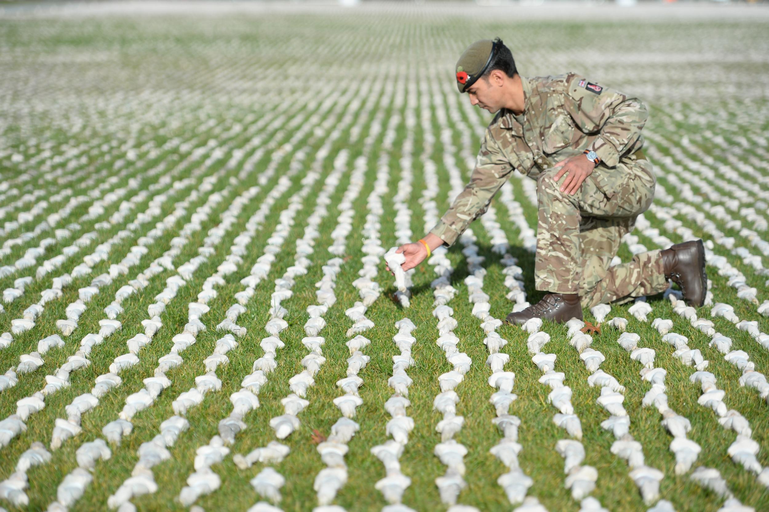 &#13;
Captain James Pugh places a figure among artist Rob Heard’s installation Shrouds of the Somme at the Queen Elizabeth Olympic Park in London (Kirsty O’Connor/PA)&#13;