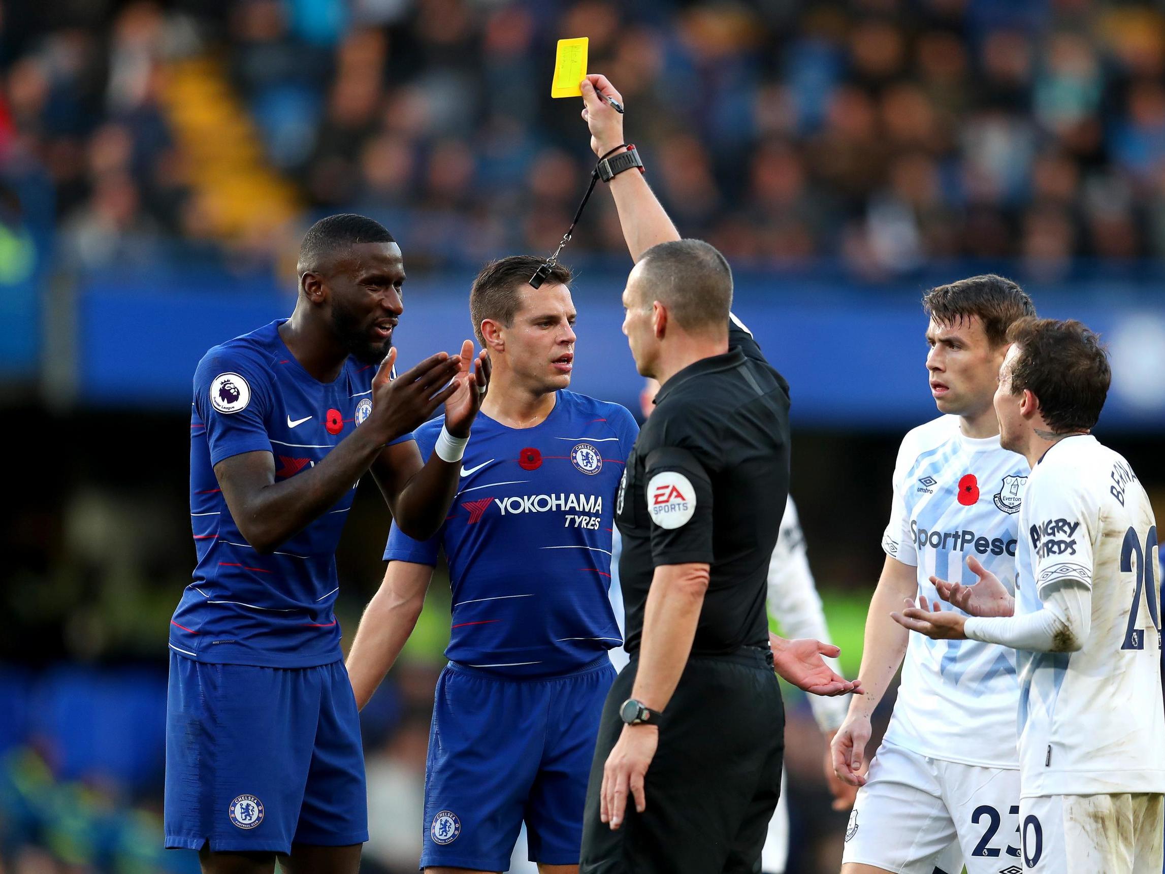 Referee Kevin Friend shows a yellow card to Antonio Rudiger