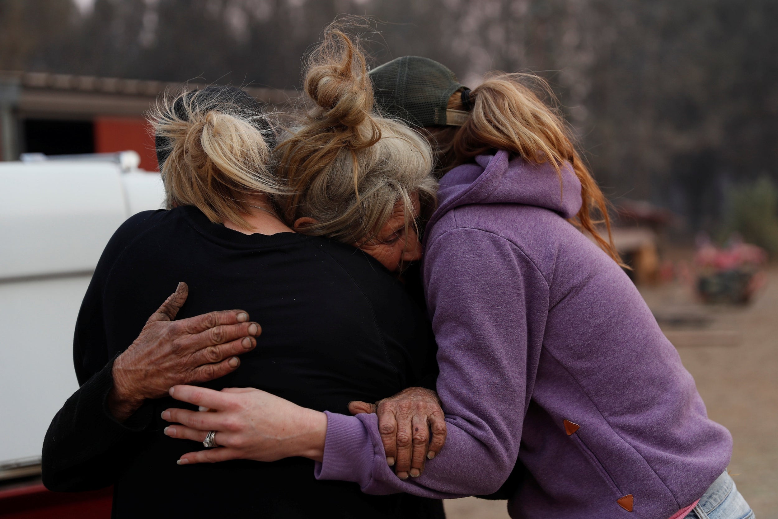 Cathy Fallon (centre) who stayed behind to tend to her horses during the Camp Fire, embraces Shawna De Long (left) and April Smith who brought supplies for the horses 