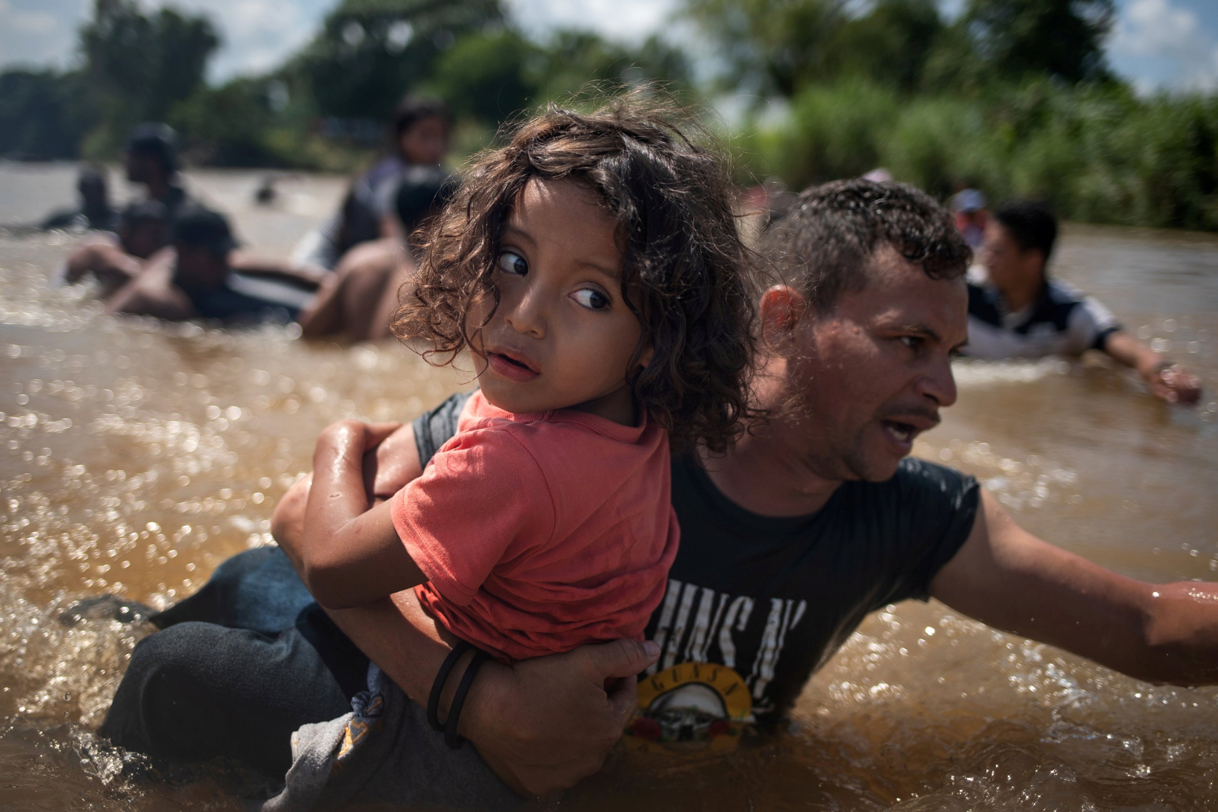 Luis Acosta holds five-year-old Angel Jesus, both from Honduras, in the Suchiate river