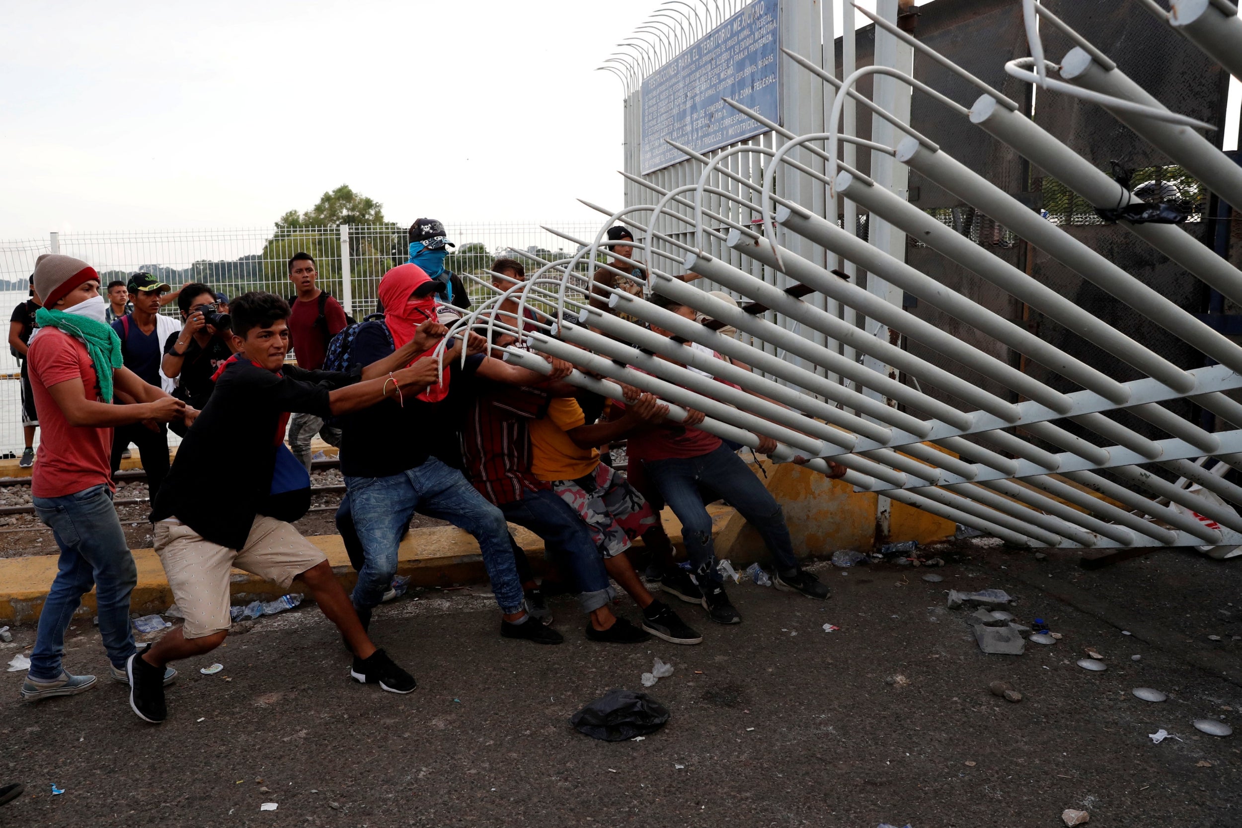 A group of men pull down the border gate in Guatemala with the intention to carry on their journey towards the US