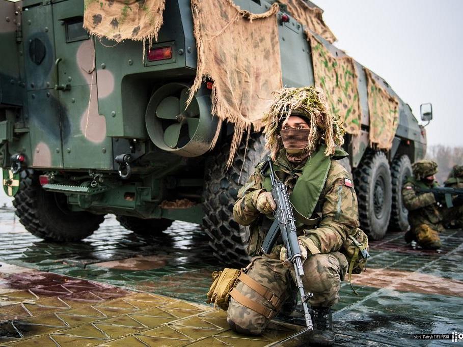 A soldier kneels next to a tank as operations get underway
