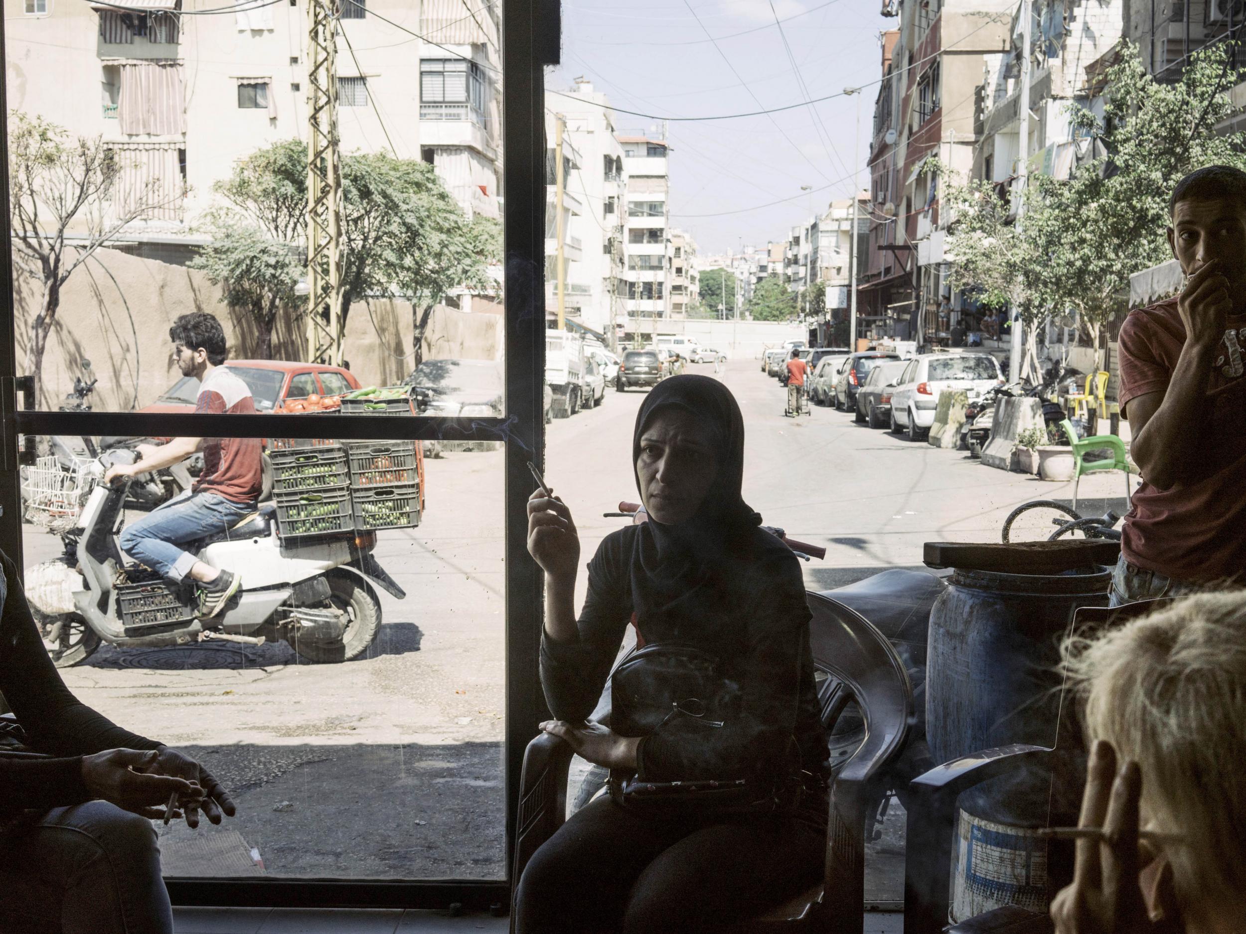 Patrons sit in a cafe at the entrance of the Bourj el-Barajneh refugee camp in the southern suburbs of Beirut