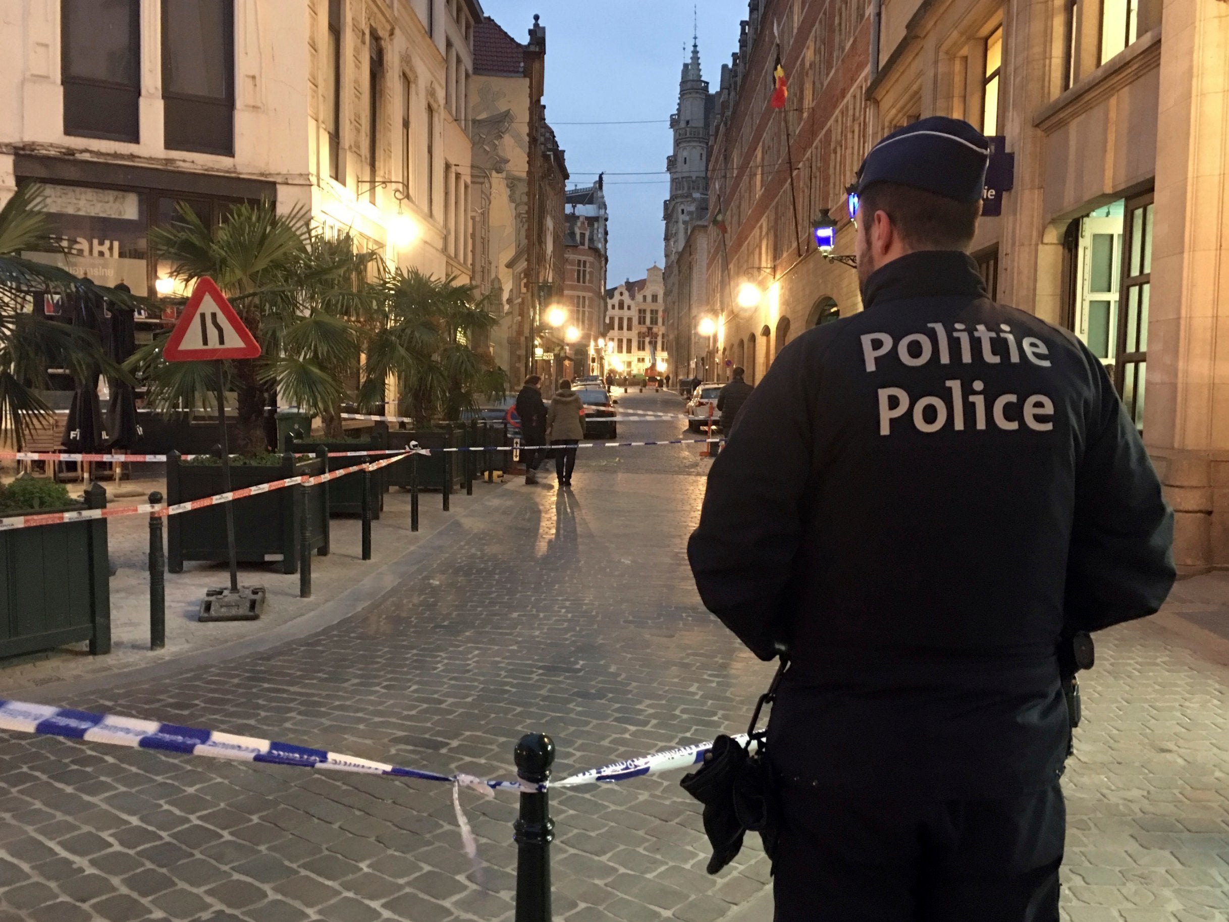 A police officer stands behind police tape during investigations at the scene of a stabbing in the centre of Brussels