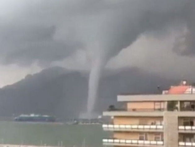 A spout forms over a body of water, but quickly dissipates over land