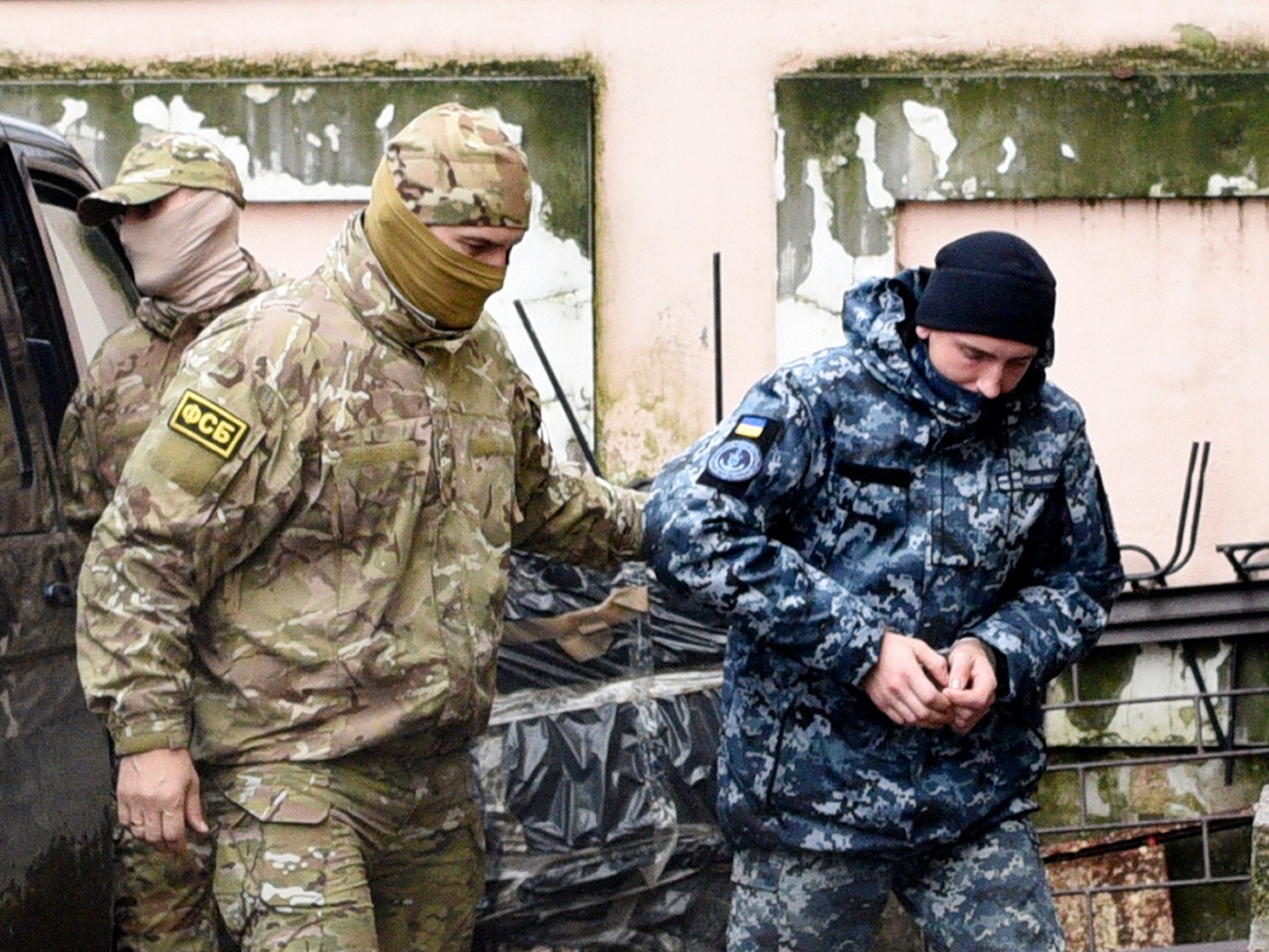 A Ukrainian sailor, right, is escorted by a Russian intelligence agency FSB officer to a court room in Simferopol, Crimea, on Tuesday