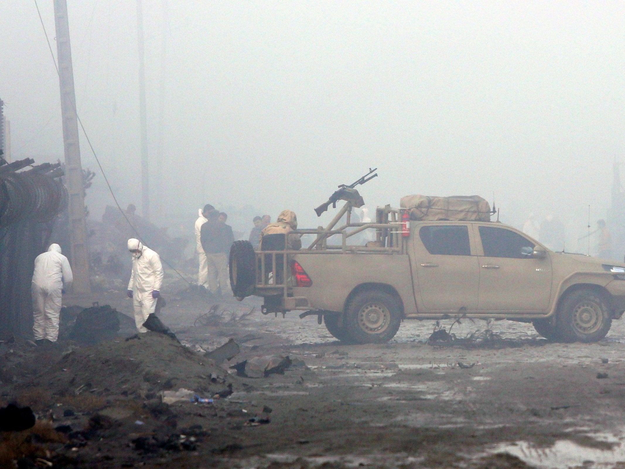 Afghan security forces inspect the site of a suicide bomb attack at a G4S compound in Kabul