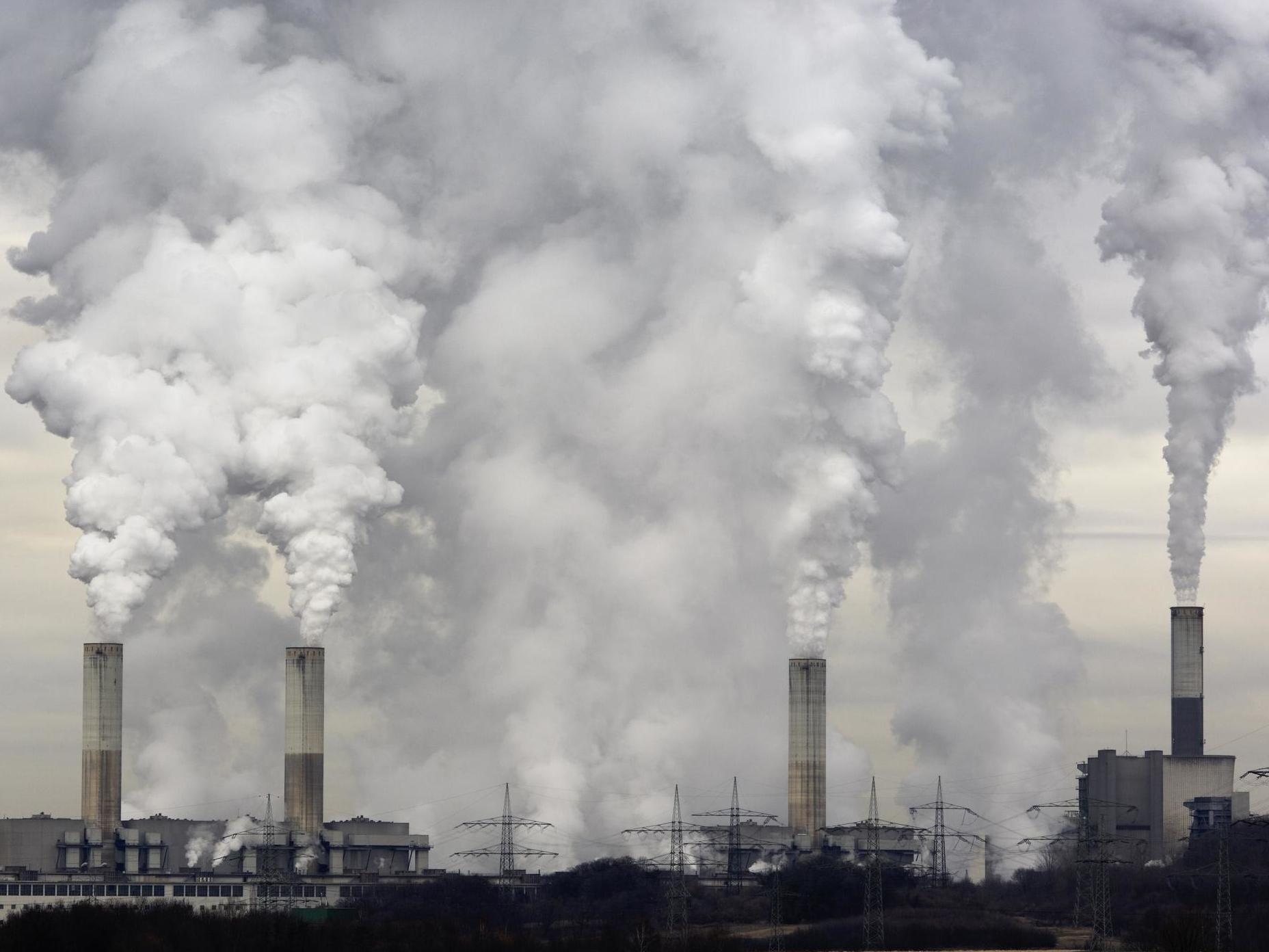 Smokestacks of a coal burning power plant with pollution on a cloudy day.