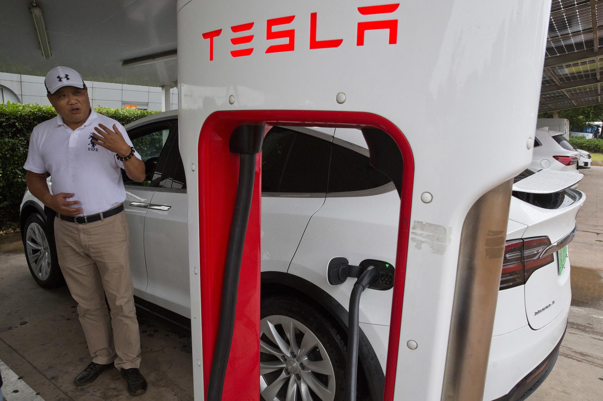 Shan Junhua chats about privacy near his white Tesla while charging it in Shanghai