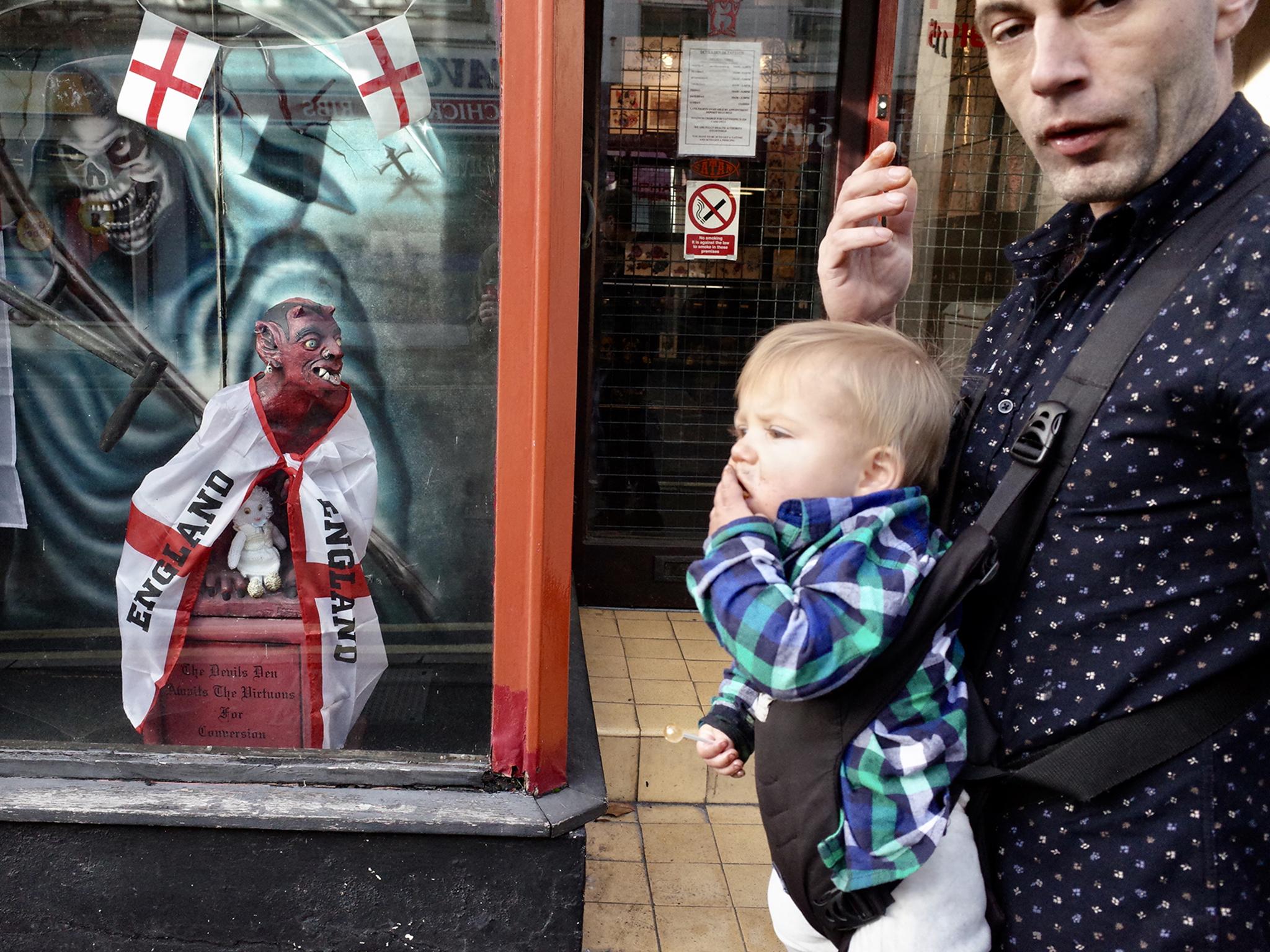 The devil draped in the St George’s cross barks from behind the window at a father and son on the street of Yeovil