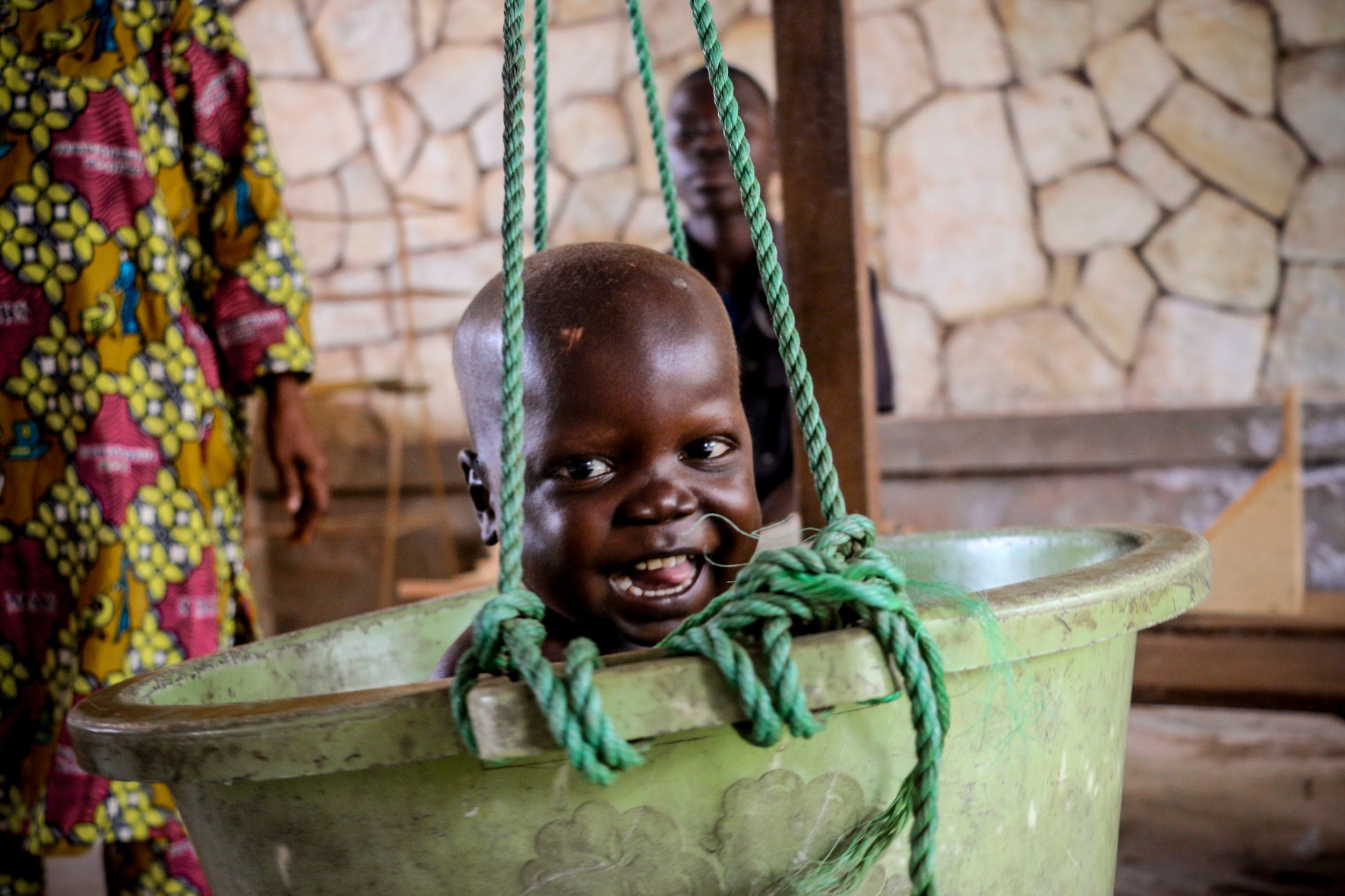 A smiling Pierre gets weighed in a health centre bucket