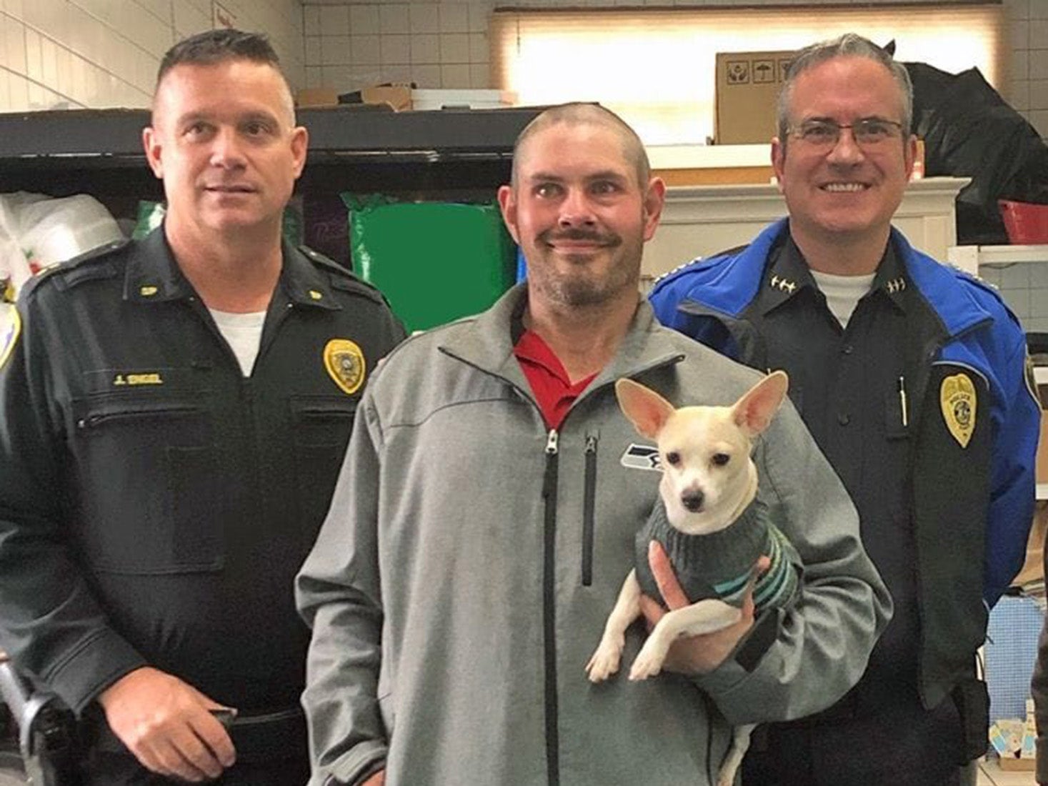 Kevin Booth holding his friend's dog with Sumner Police officers