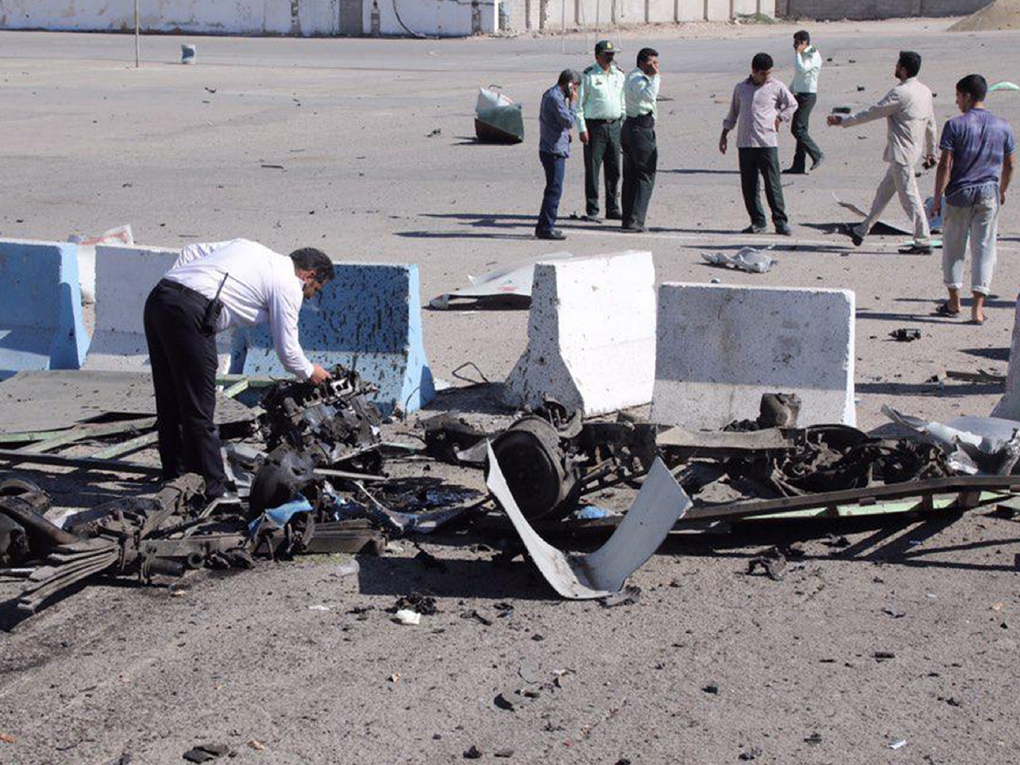 An officer inspects the vehicle wreckage outside a police station