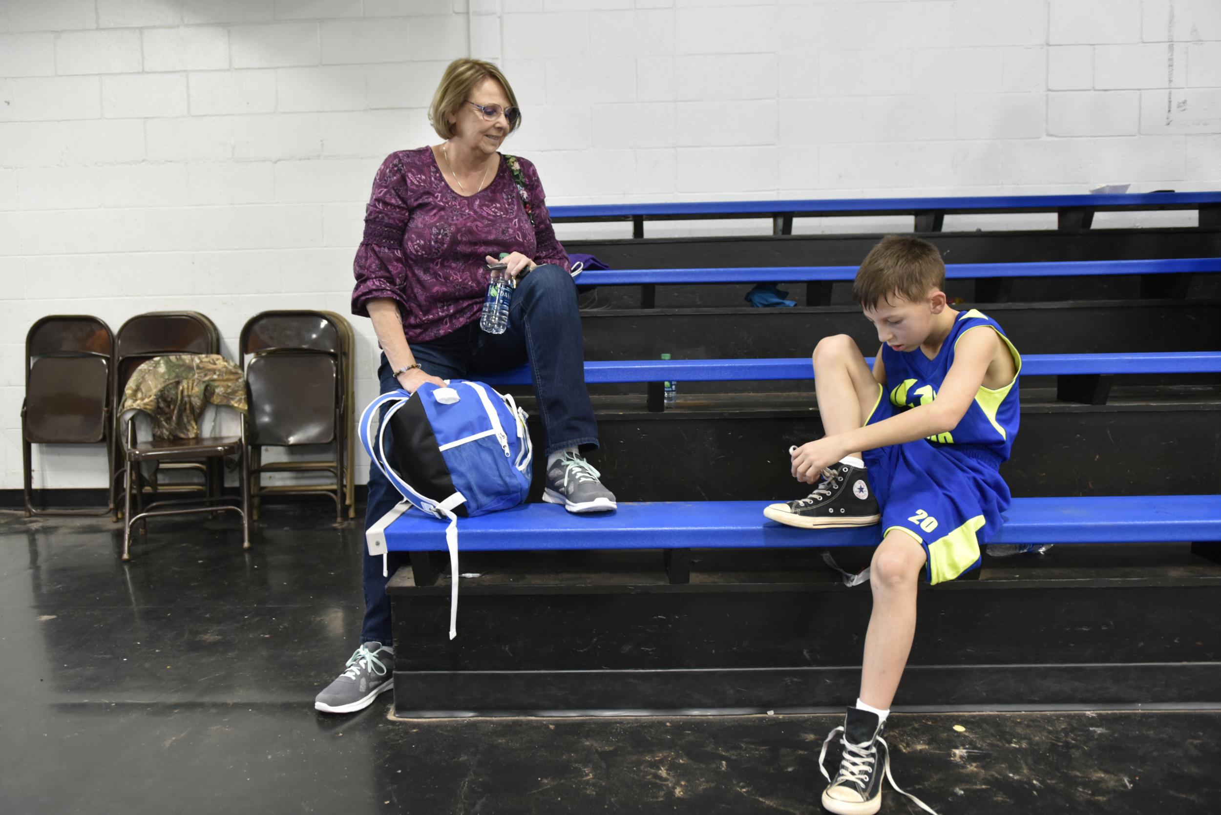 Carolyn Parnell watches her grandson Easton tie his shoes after a basketball game in Norman, Okla. His mother, Desirae Parnell, was killed by his father in 2016