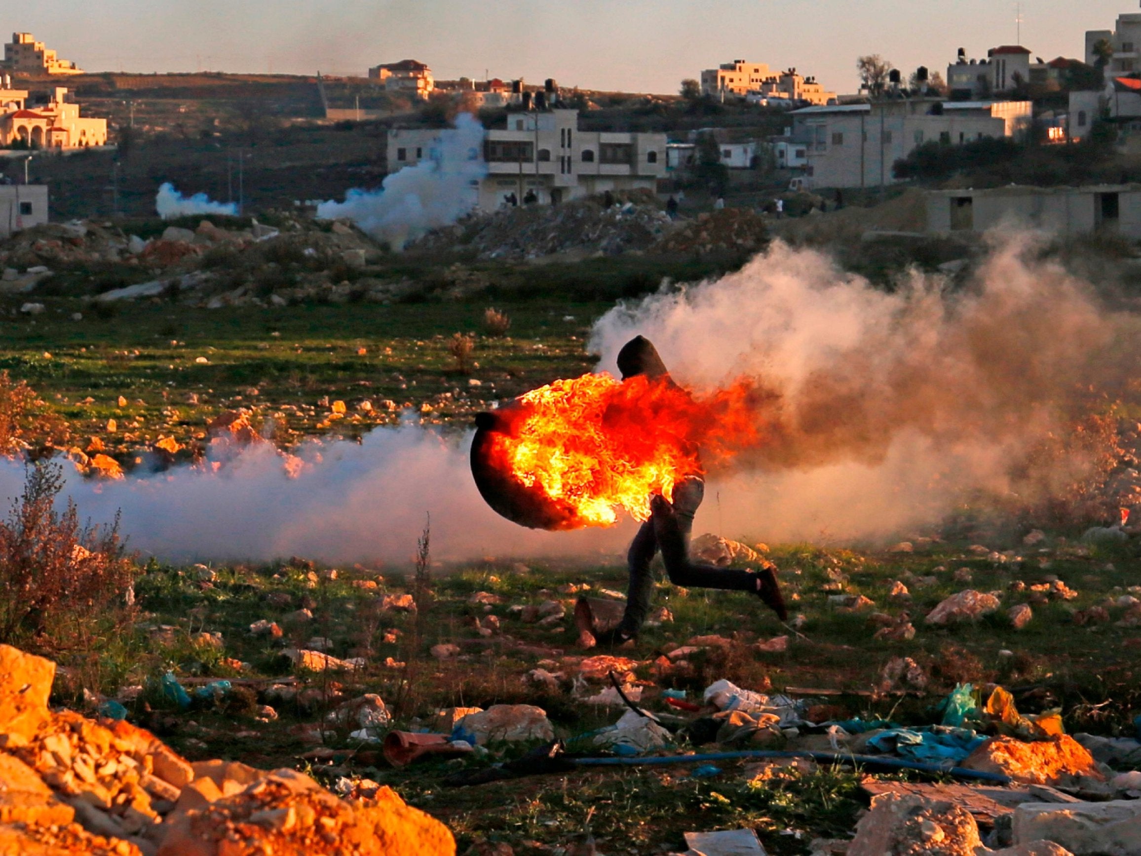 A Palestinian protester on Friday runs with a burning tire during clashes with Israeli troops in Ramallah