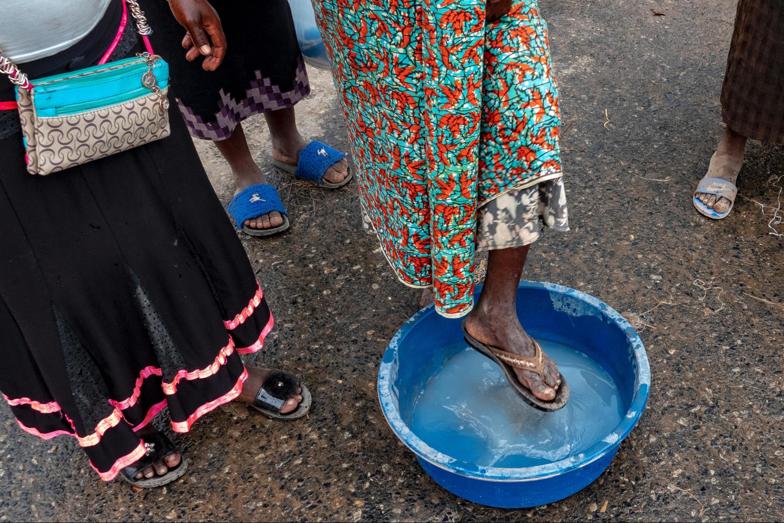 Pedestrians dip their shoes in a disinfecting solution as they cross the border from Congo into Uganda (The Washington Post)