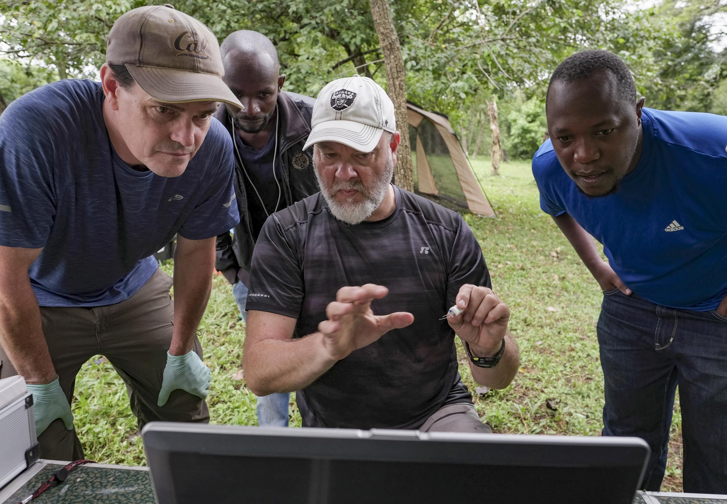 CDC scientist Brian Amman, centre, discusses tracking software with colleague Jonathan Towner, left, as Luke Nyakarahuka and Apollo David Bogere observe (The Washington Post)