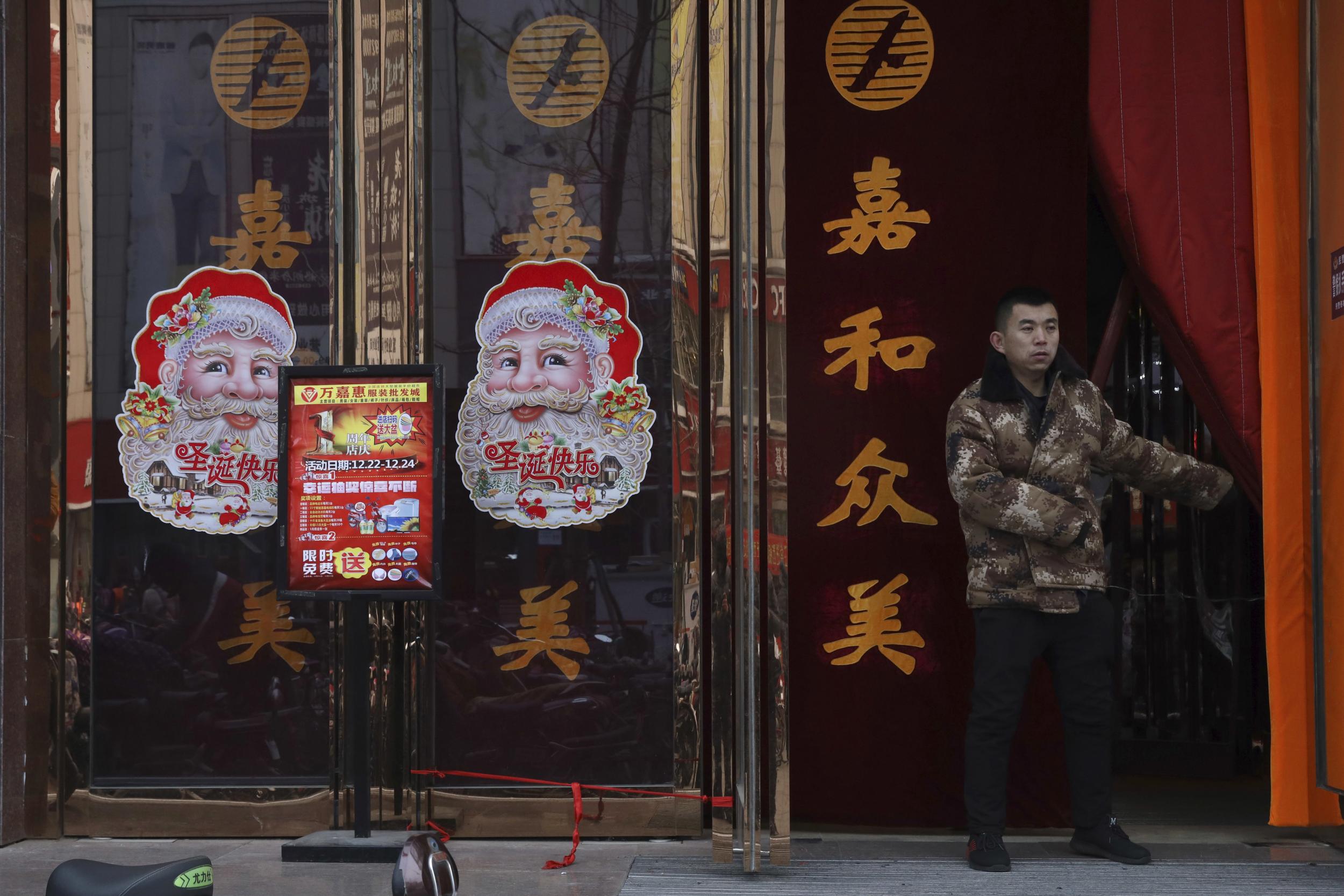 A worker guards the entrance of a shop decorated with images of Santa Claus in Zhangjiakou in northern China's Hebei province.