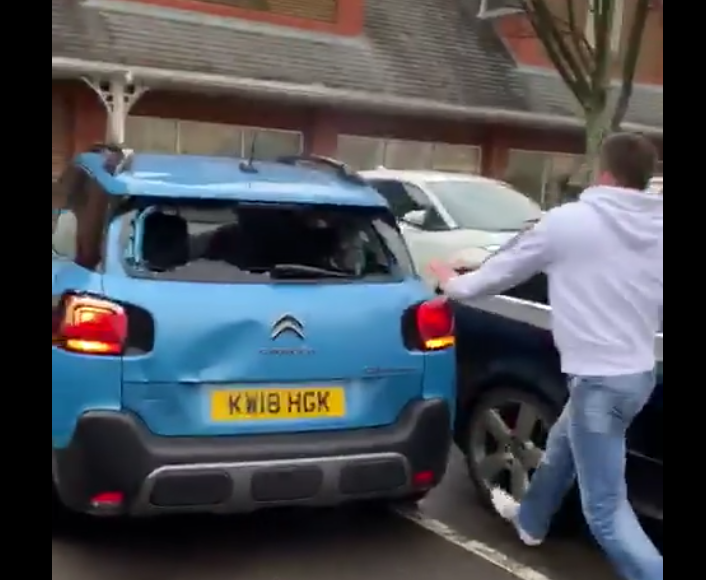 Man wielding a metal bar attempts to hit windows as car tries to escape