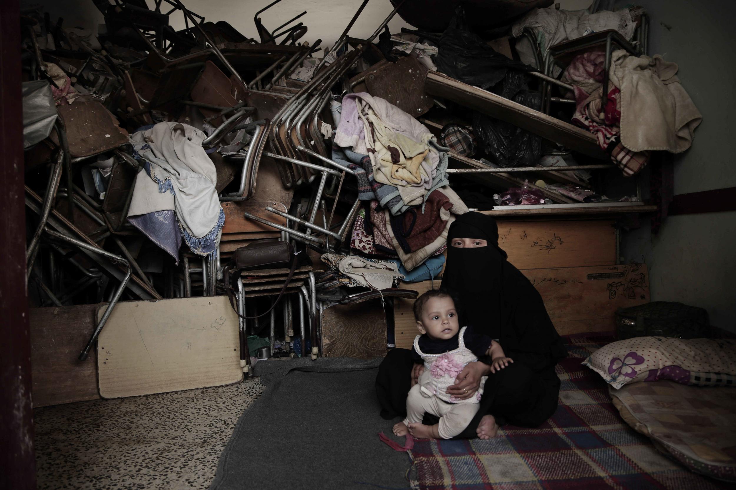 A woman sits with her baby inside a shelter for displaced persons in Ibb, Yemen, in this 3 Aug 2018 photo.