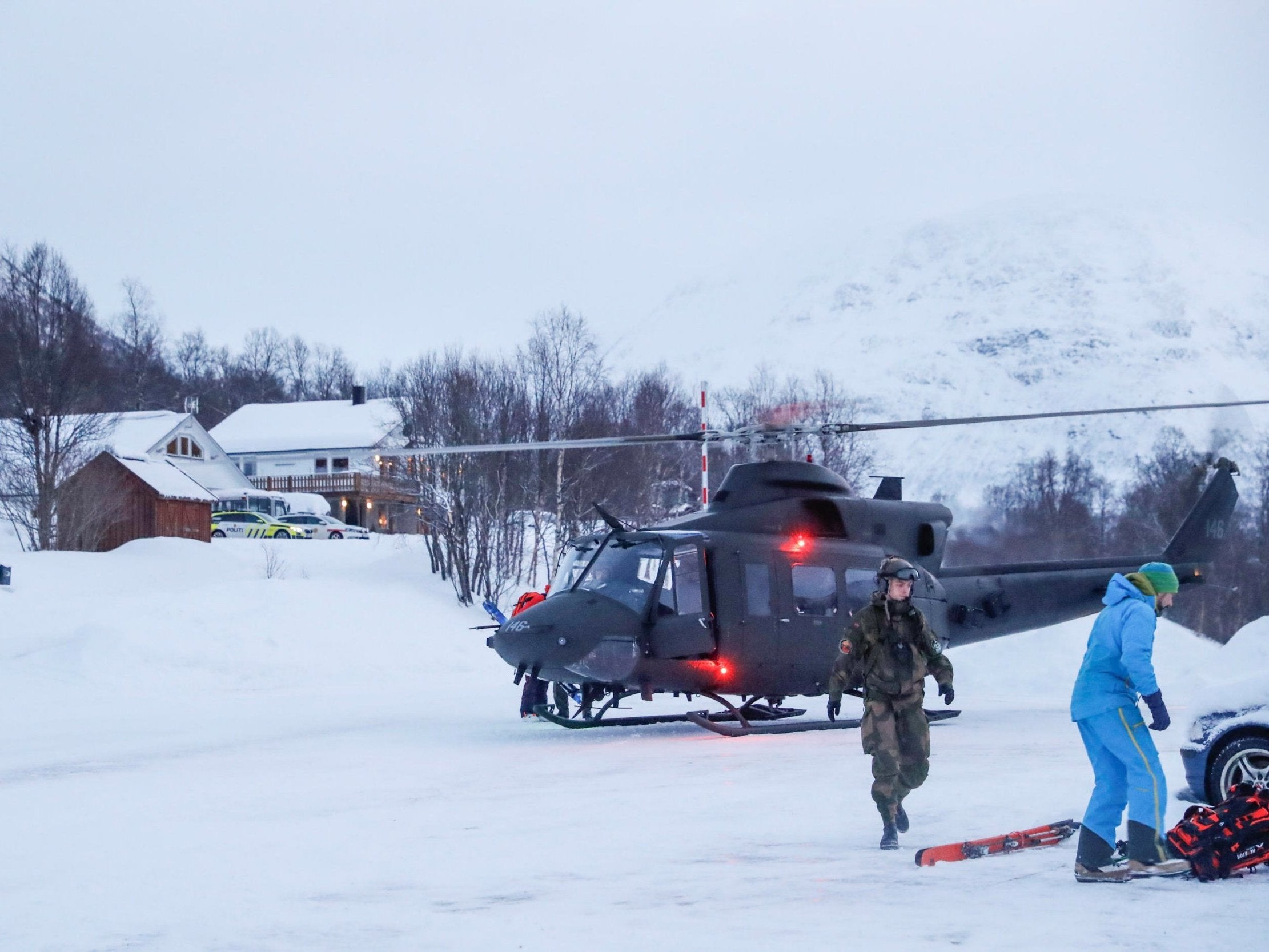 A military helicopter and rescue workers search for the skiers in Tamokdalen, northern Norway