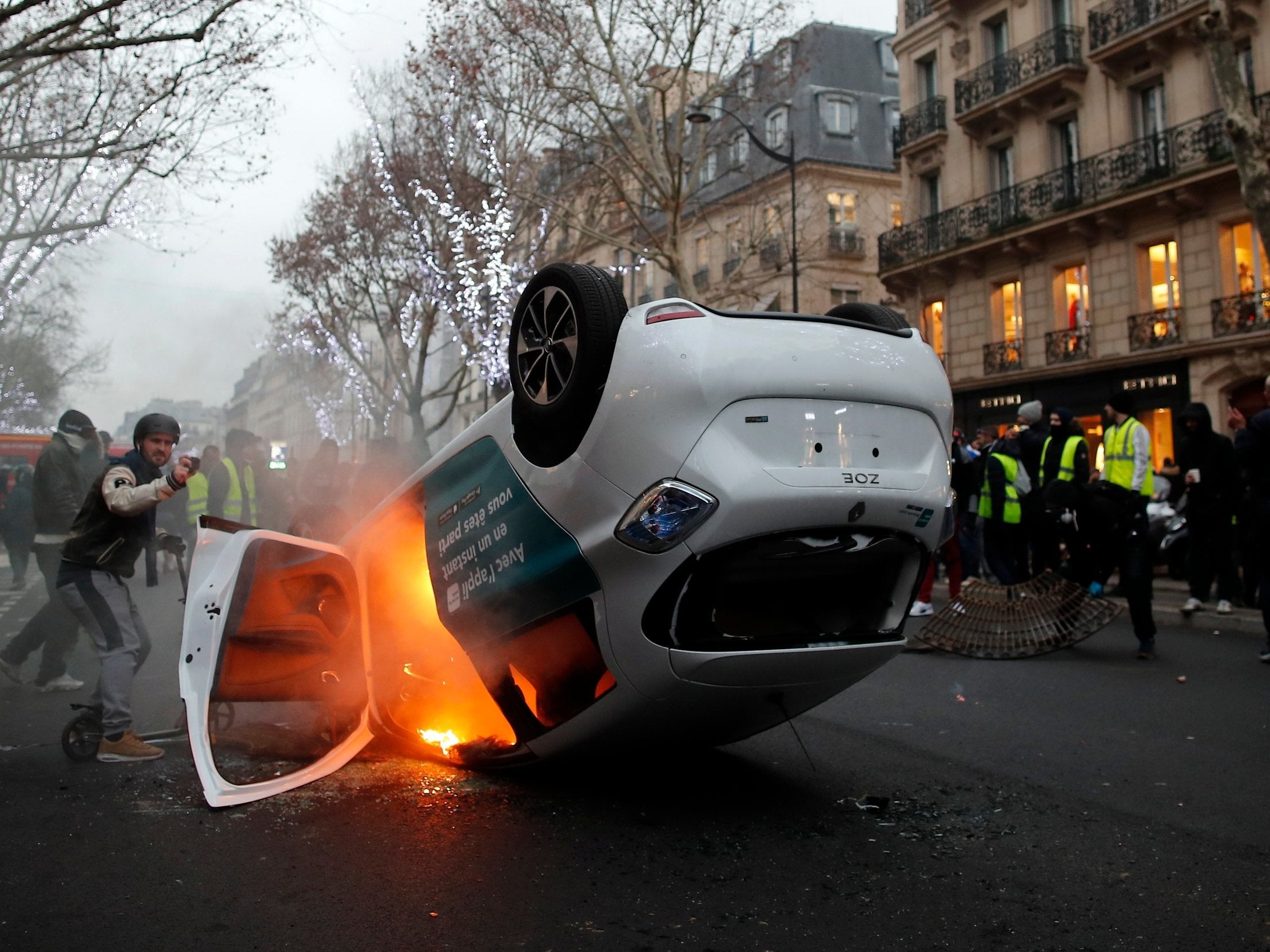 An overturned car burns during demonstration