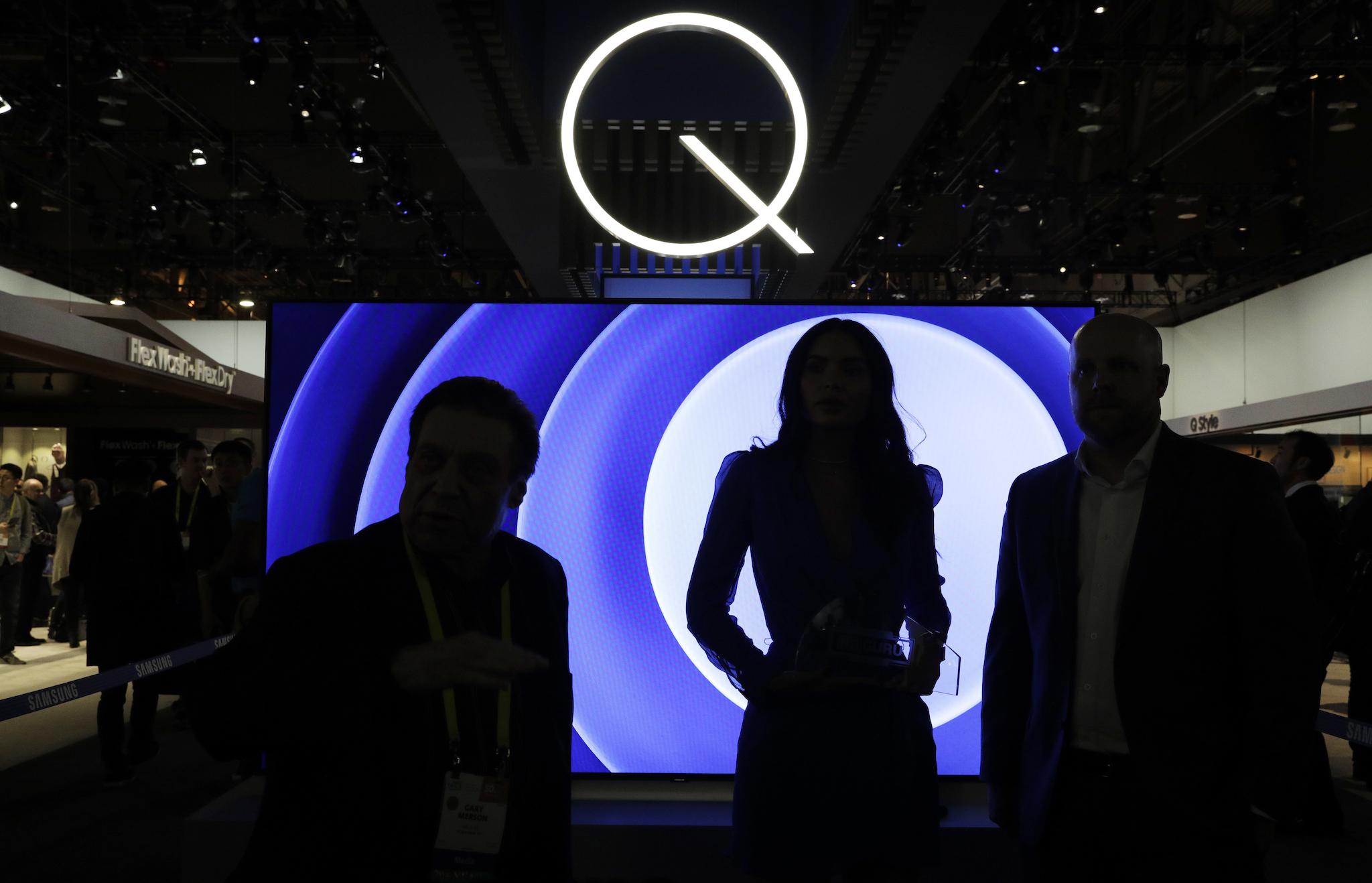 Attendees stand in front of a QLED TV at the Samsung booth during CES International in Las Vegas