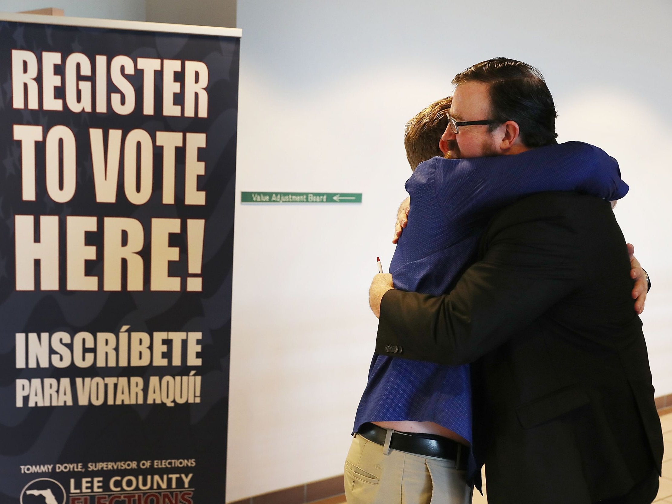 Lance Wissinger and Neil Volz hug after turning in their voter registration forms at the Lee County Supervisor of Elections office on 8 January 2019 in Fort Myers, Florida