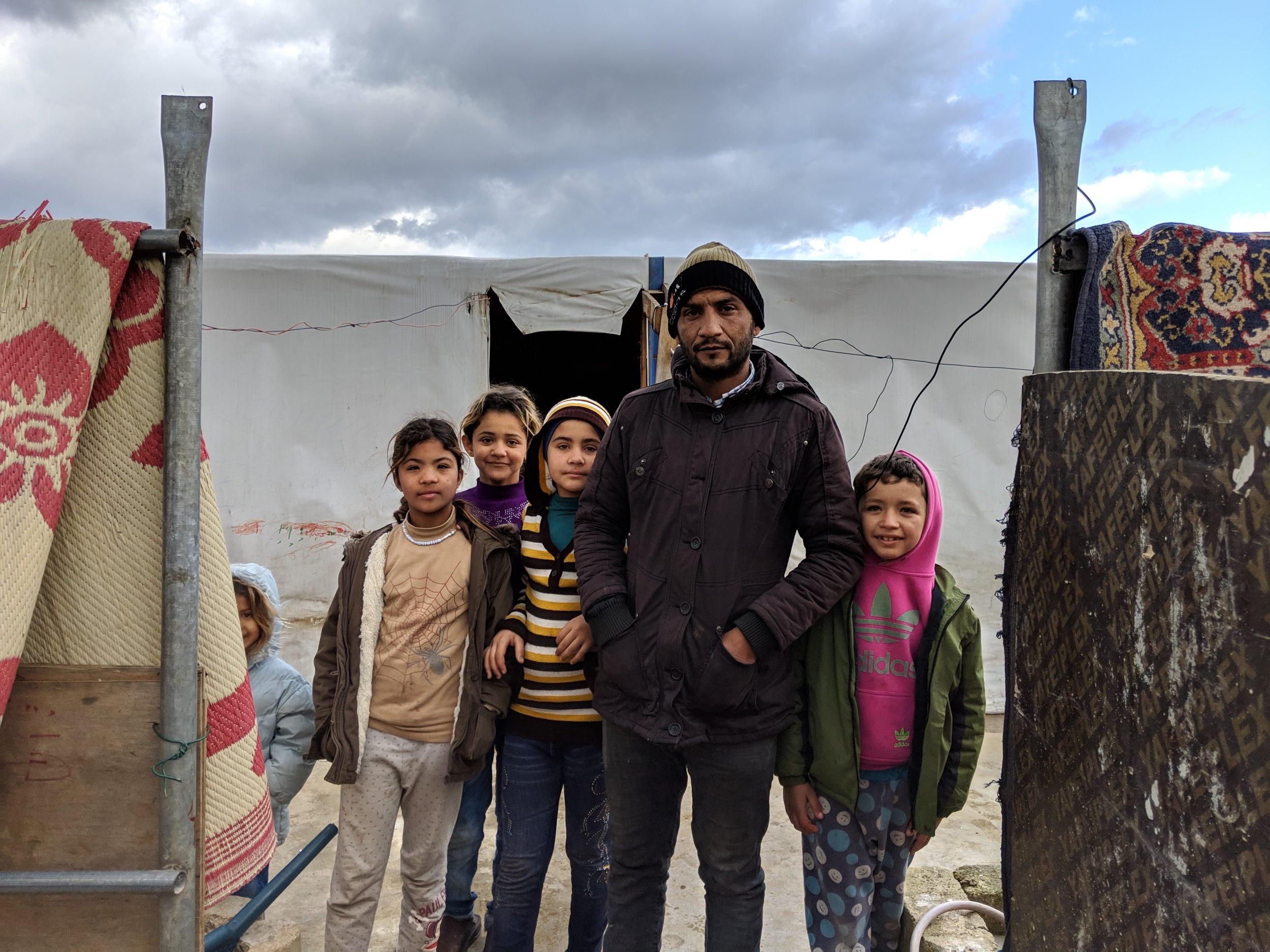 Khaled Alawi stands with his daughters in front of his home in an informal settlement for Syrian refugees in Akkar, northern Lebanon