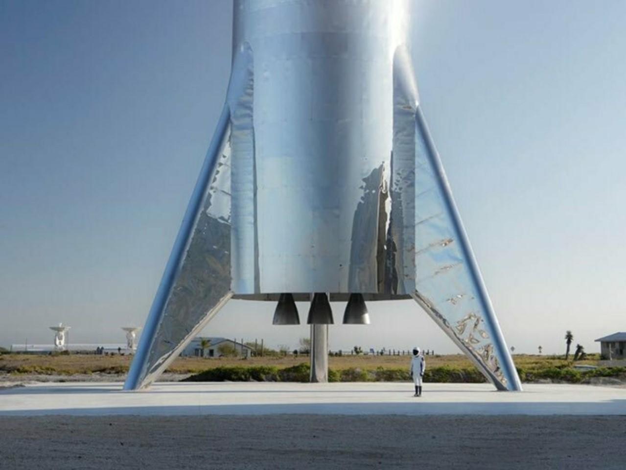 A person stands beside the Starship test flight rocket at the SpaceX Texas launch site