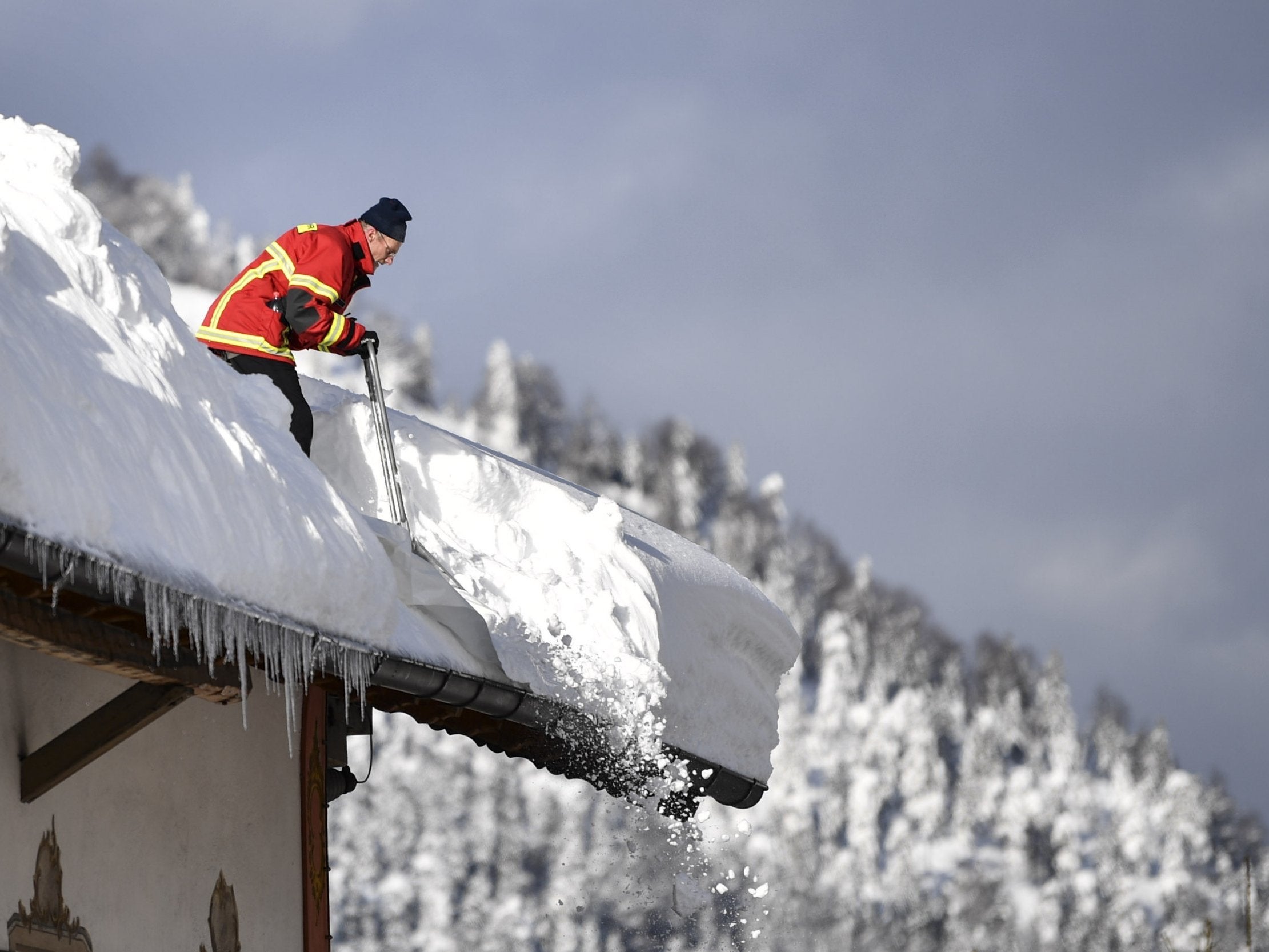 A fireman clears a roof following heavy snowfall in Kruen, Germany