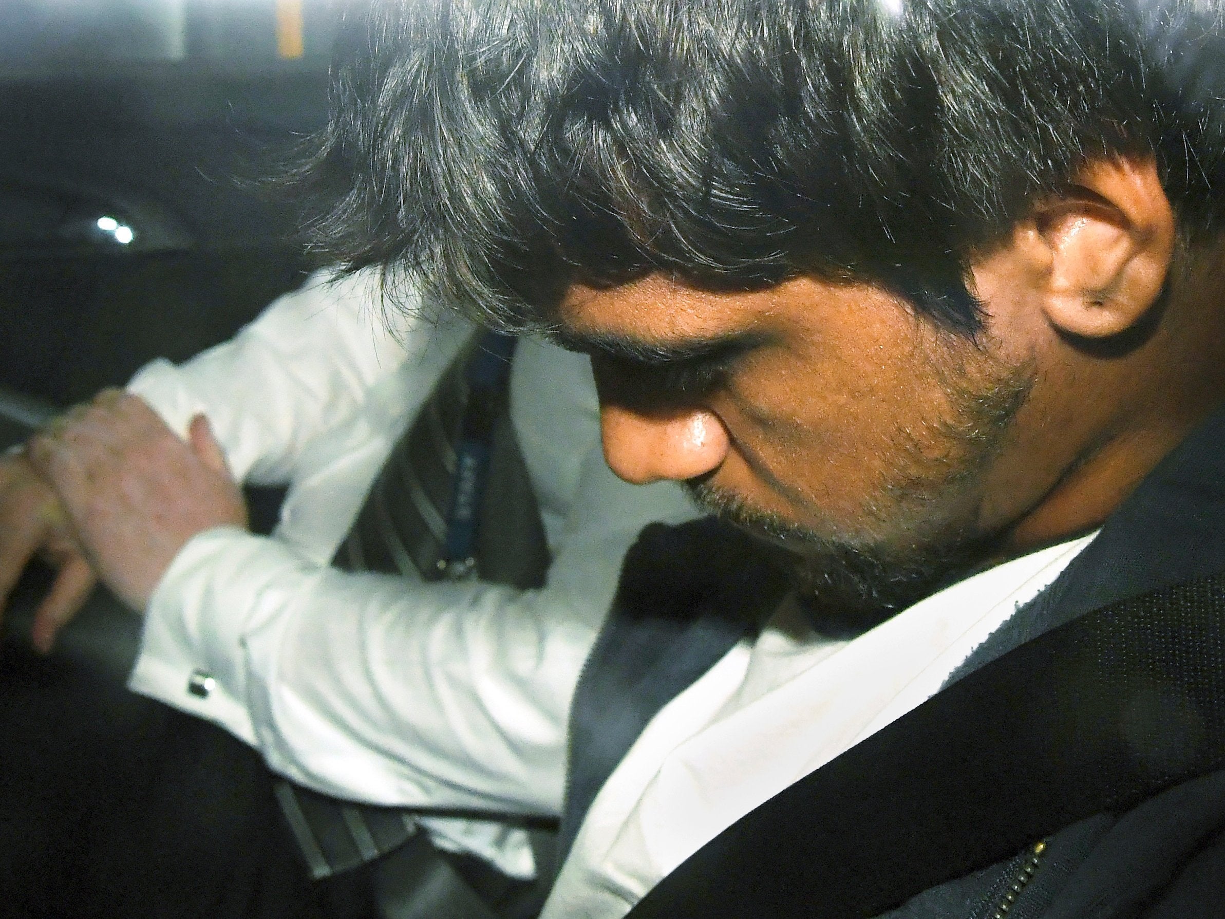 A 20-year-old man sits in a police car after he was arrested for questioning over the death of Israeli student Aiia Maasarwe in Melbourne