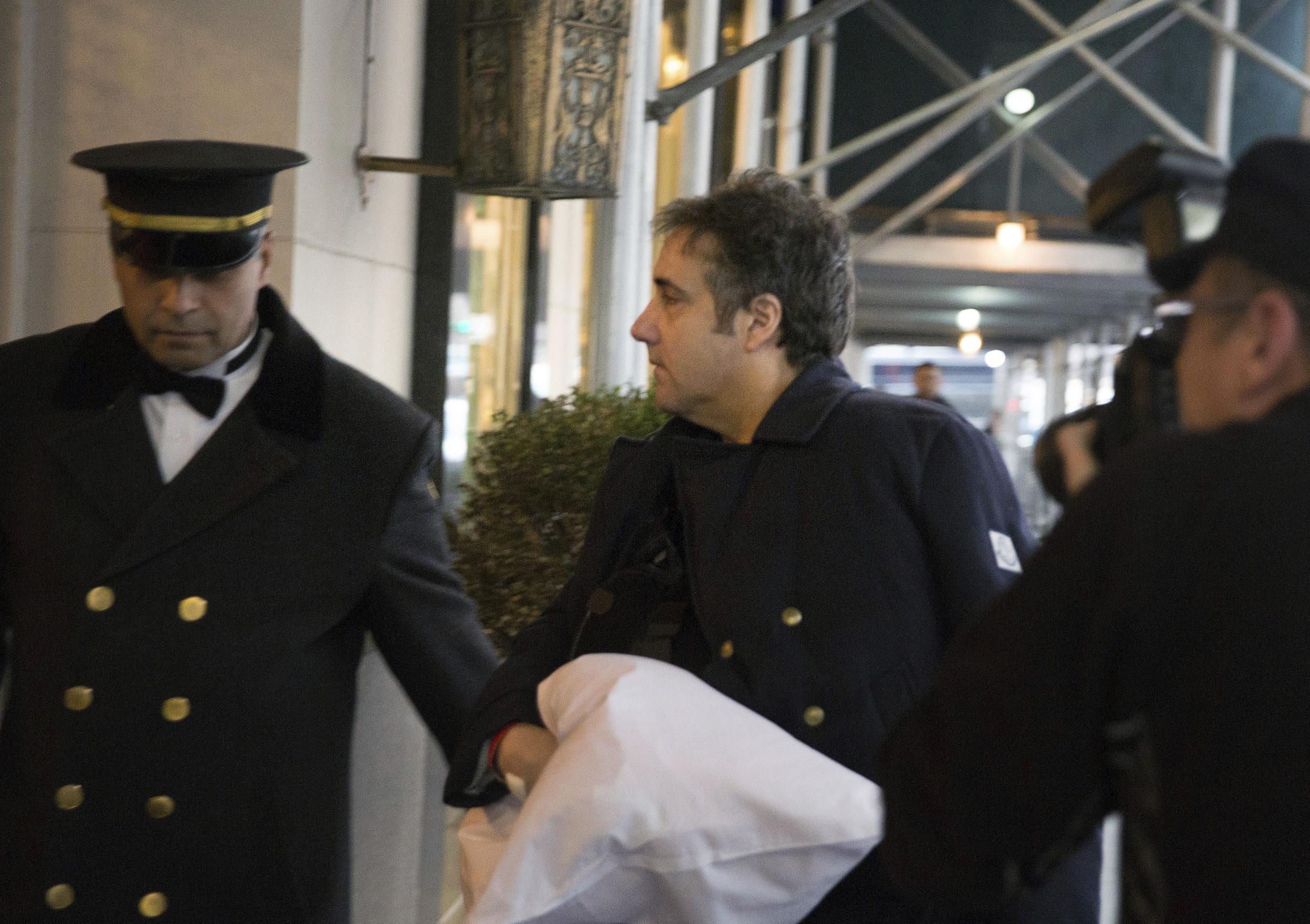 Michael Cohen arrives at his home in New York with his left arm in a sling supported by a pillow Friday