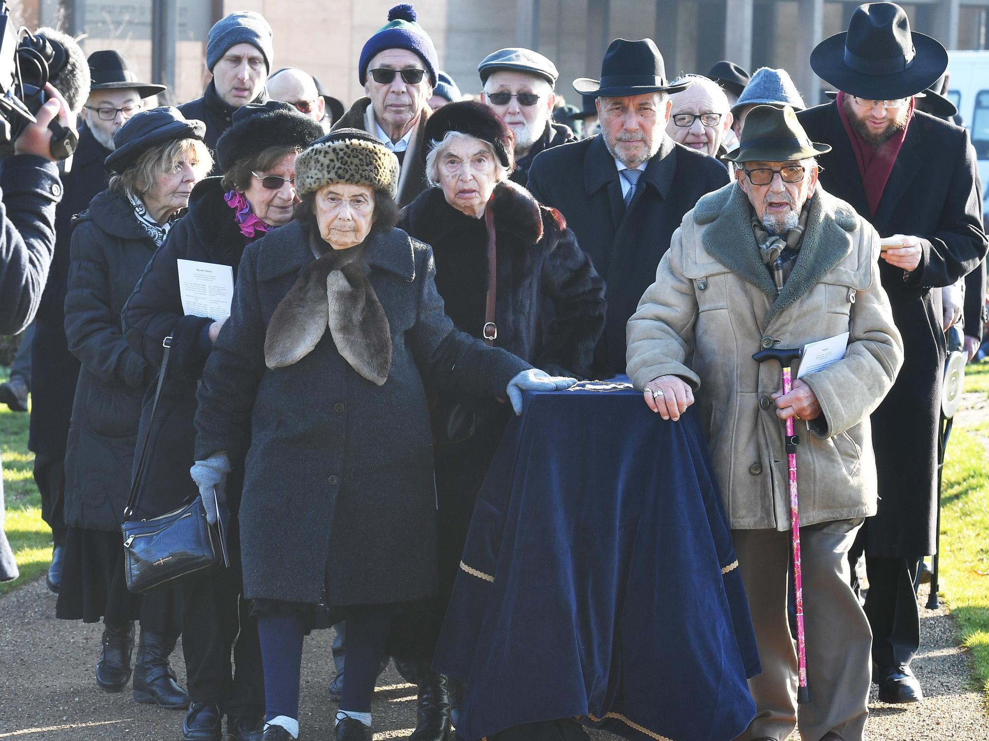 A group of survivors of the Holocaust wheel a covered coffin with the remains of six unknown Jews murdered at Auschwitz