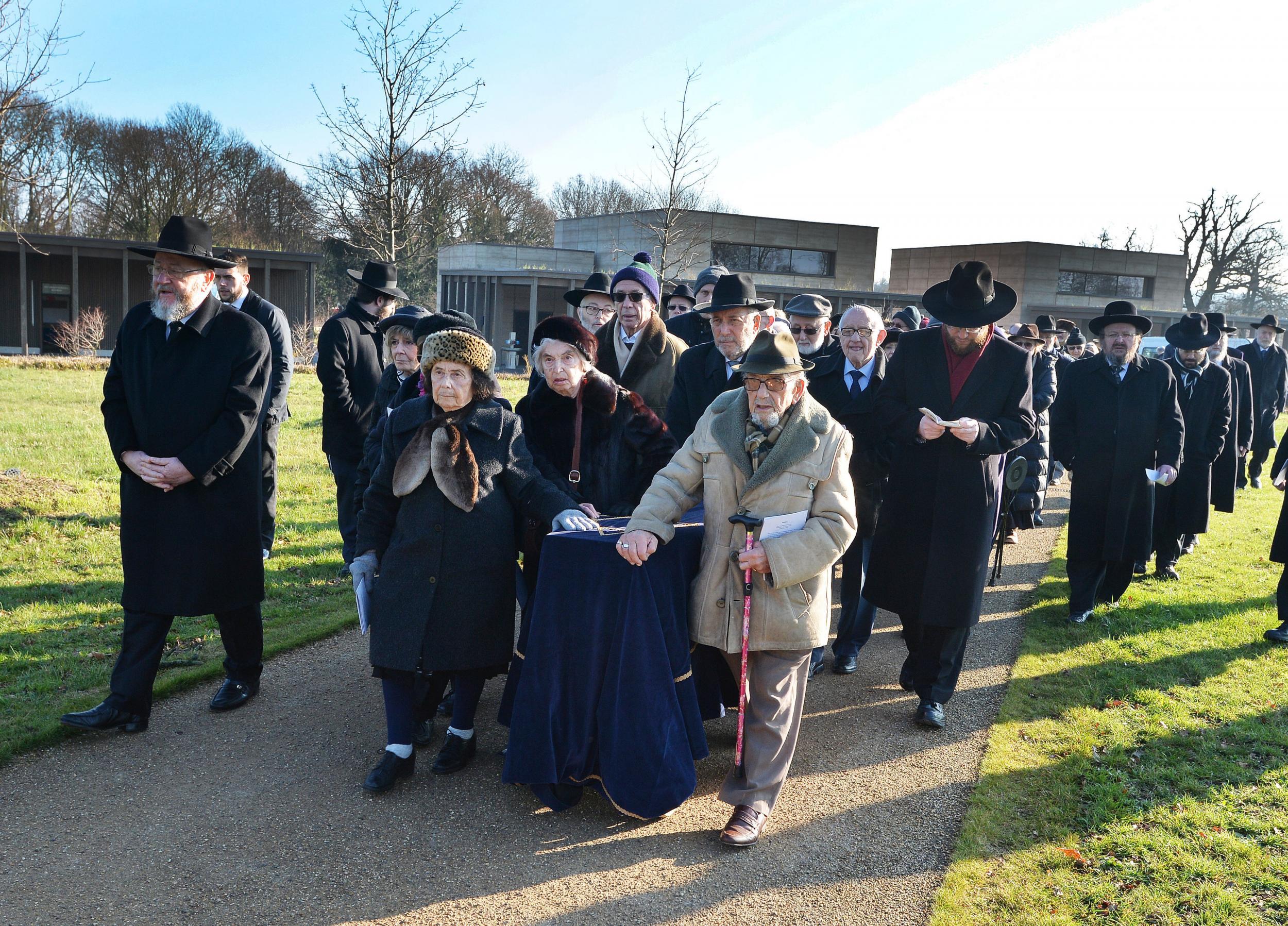 Holocaust survivors wheel a coffin containing the remains of six unknown Jews murdered at Auschwitz