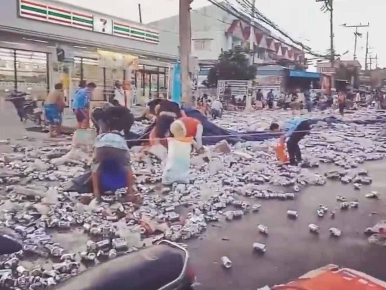 Video footage captured locals gathering up beer cans after a lorry overturned in Phuket, Thailand