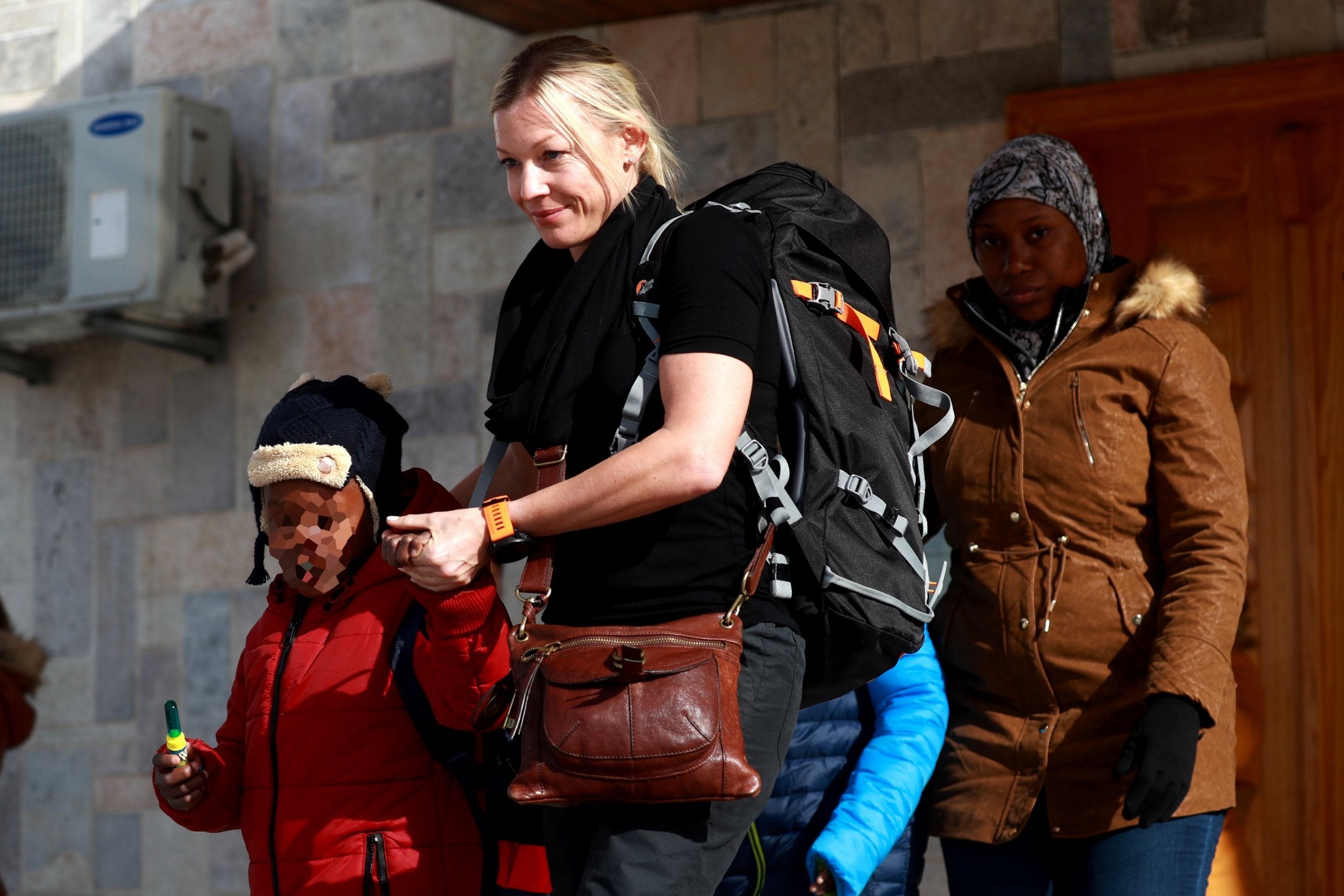 A member of an NGO accompanies two Caribbean children and their mother (R) as they prepare to leave the northeastern Syrian Kurdish-majority city of Qamishli on January 21, 2018