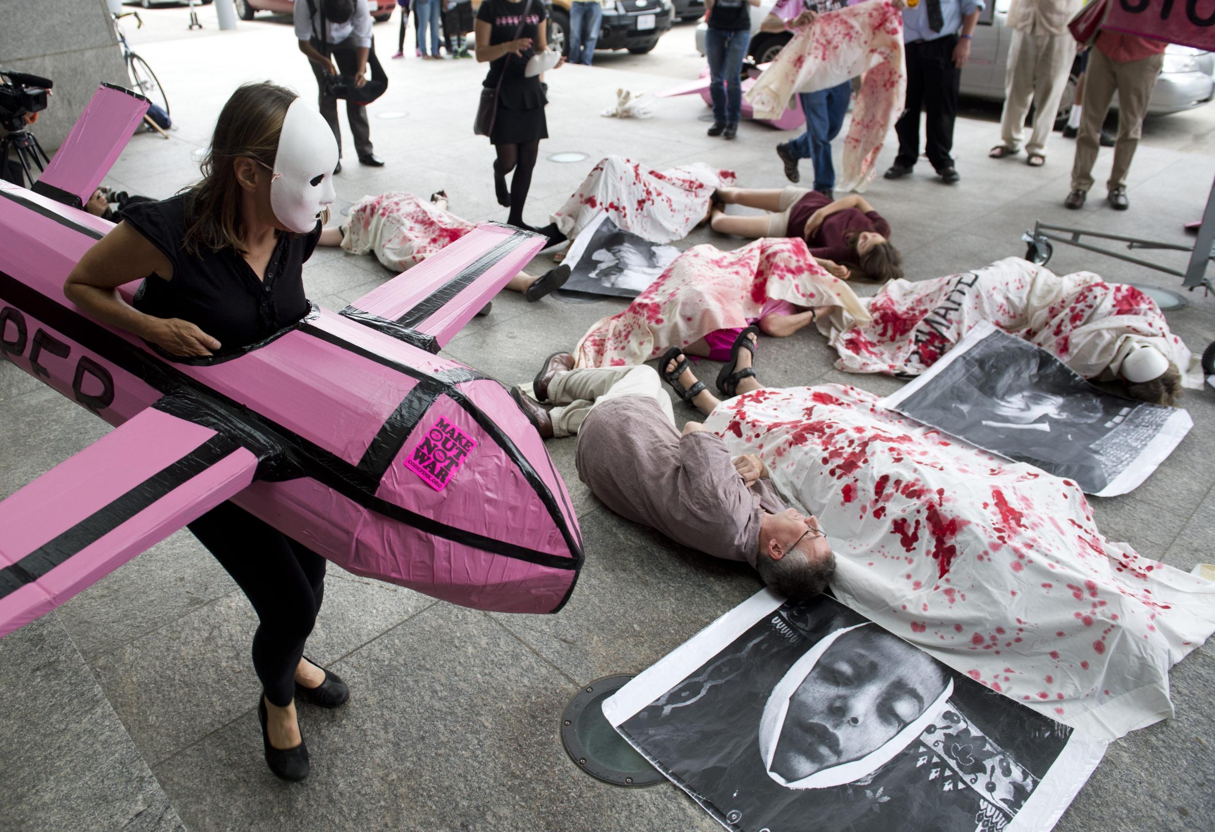 Codepink protestors perform mock killings as they demonstrate use of military drones - or flying robots - by the US goverment outside the Unmanned Systems 2013 exhibition, Washington, 13 August 2013. (Saul Loeb/AFP/Getty Images)