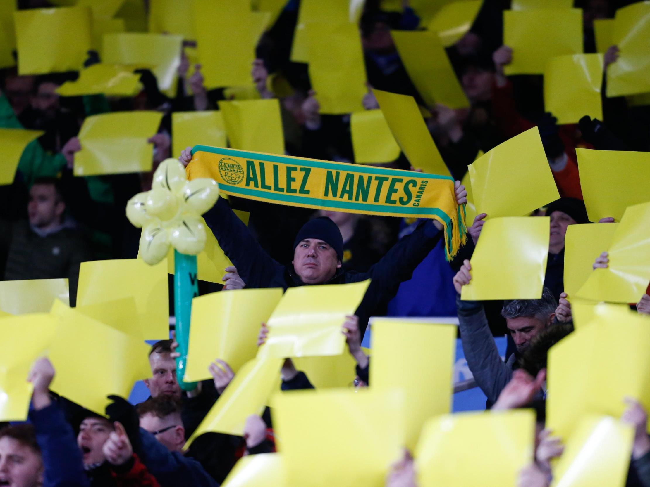 Fans hold up yellow banners and a Nantes scarf in honour of Cardiff City’s missing player Emiliano Sala