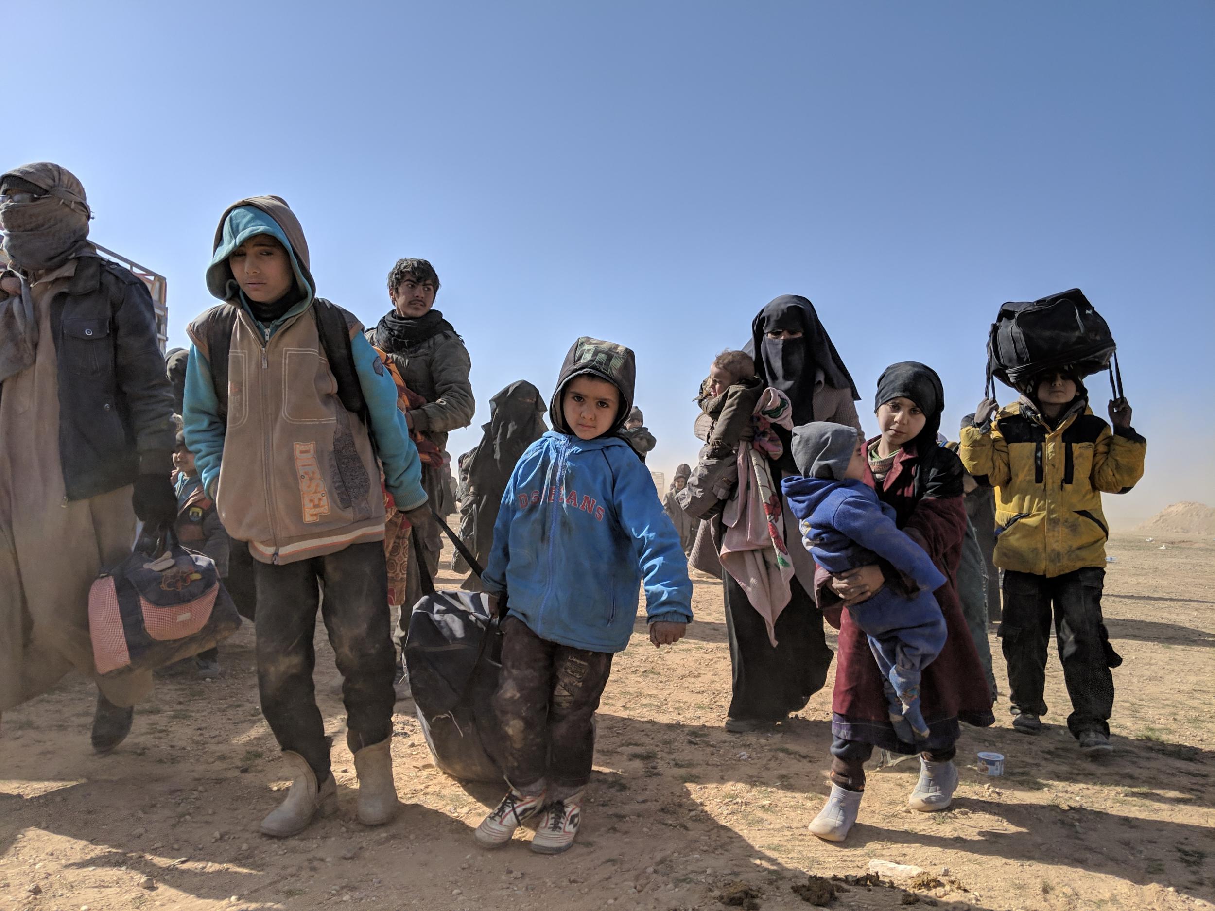 Trucks full of women and children arrive in the desert to the east of Hajin, near the Iraqi border, on Saturday 26 January (Richard Hall/The Independent)