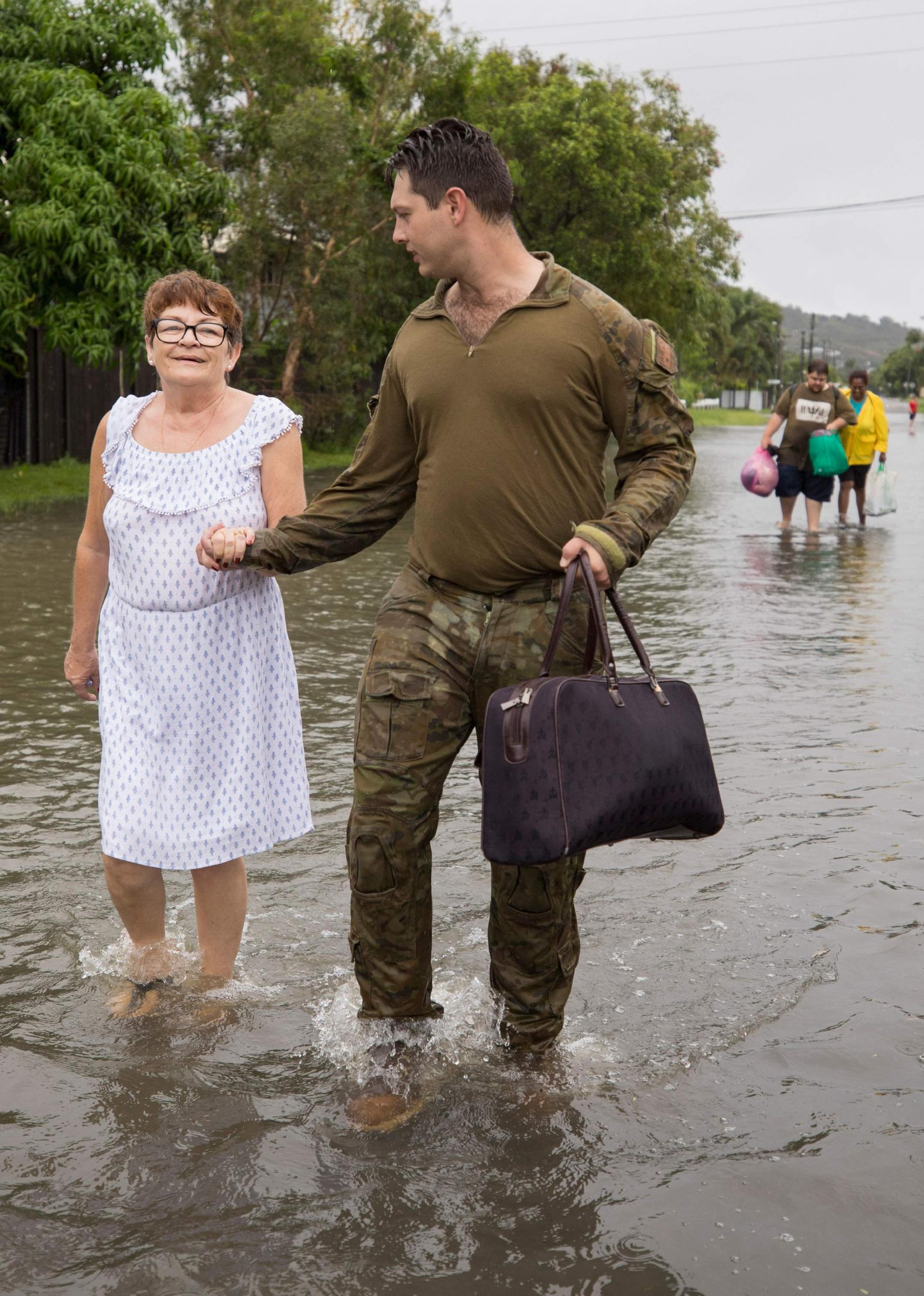 An Australian soldier helps a Townsville resident evacuate her home as the military is deployed to tackle the floods on February 4