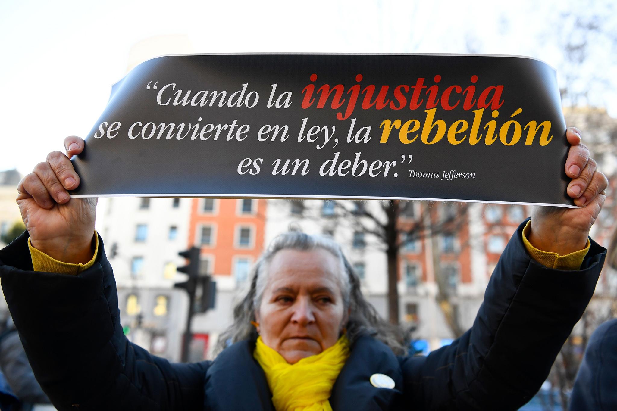 A separatist protester holds a sign reading "When injustice becomes law, rebellion is a must" outside the Supreme Court in Madrid