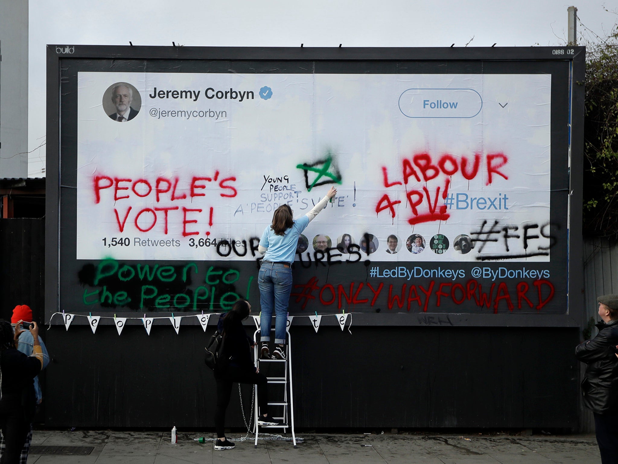 Young campaigners deface a Labour Party billboard, calling for a fresh vote