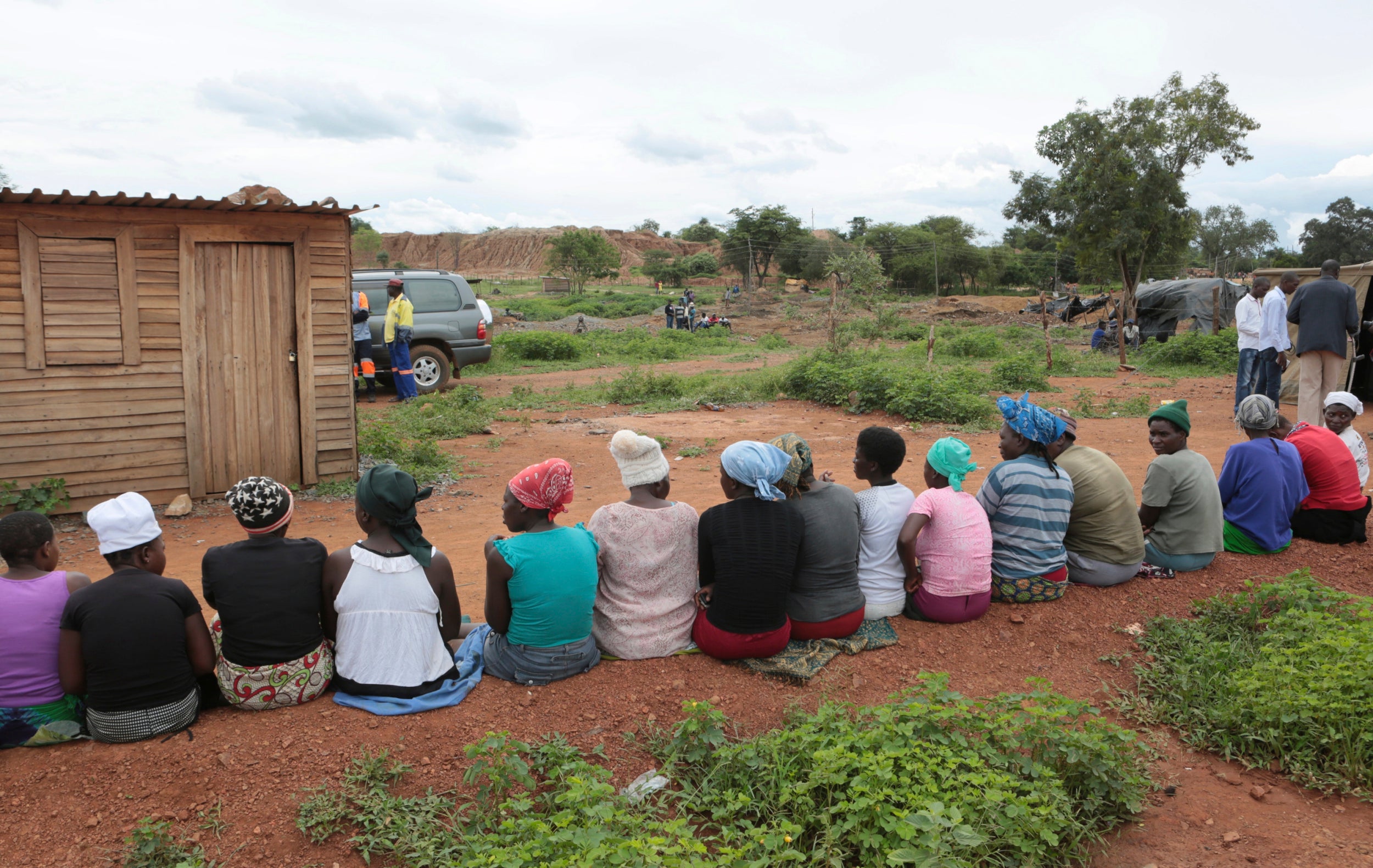 Wives of trapped miners gather together near the mine where some tens of artisanal gold miners are feared dead after rains flooded the mines while they were underground on the outskirts of Kadoma town about 200 kilometres west of Harare, Zimbabwe, Thursday, Feb, 14, 2019.  Hopes of rescuing the trapped miners are fading due to lack of necessary equipment after they were reported missing Wednesday.