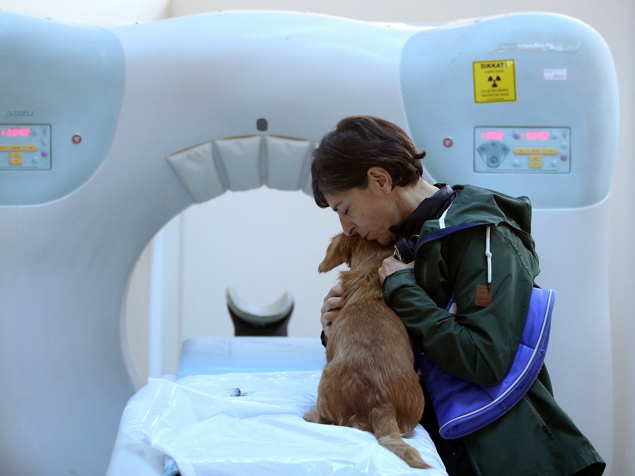 A woman hugs her dog before a tomography screening