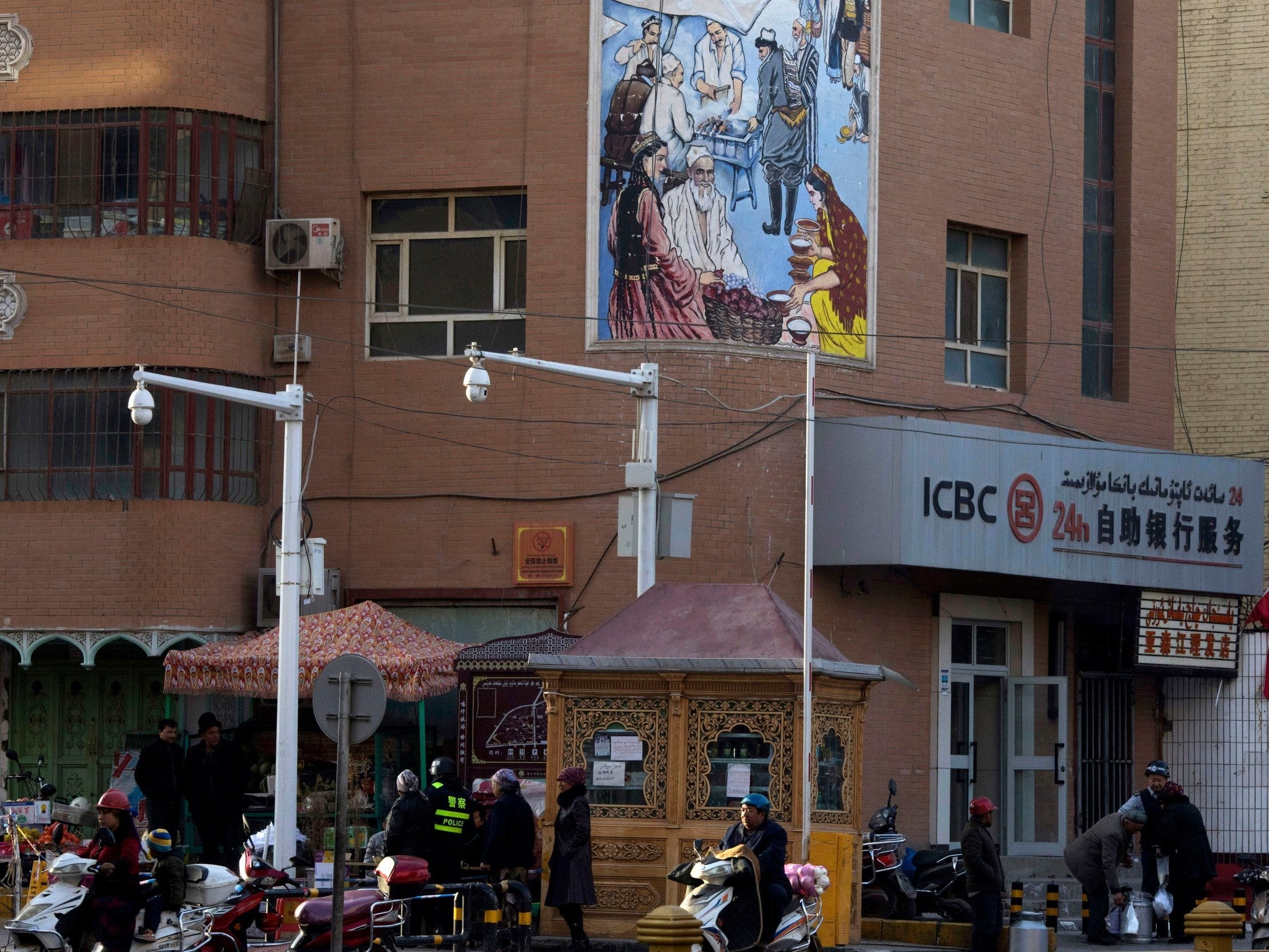 People pass by a security checkpoint and surveillance cameras on a street in Kashgar in China's Xinjiang region