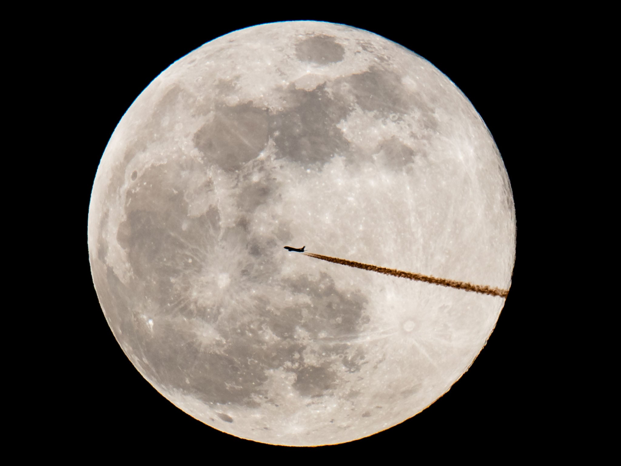 A plane flies past the snow moon in Nuremberg, Germany