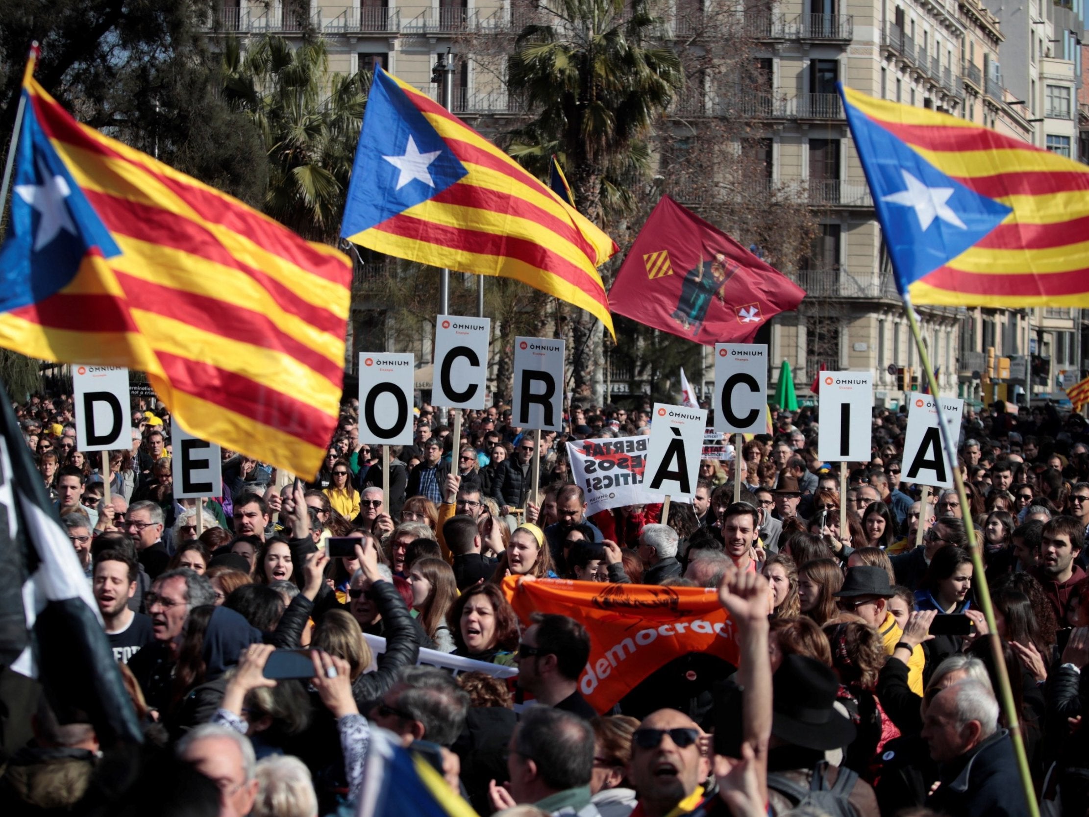 Demonstrators hold banners reading ‘Democracy’ during a pro-independence rally at Barcelona University Square